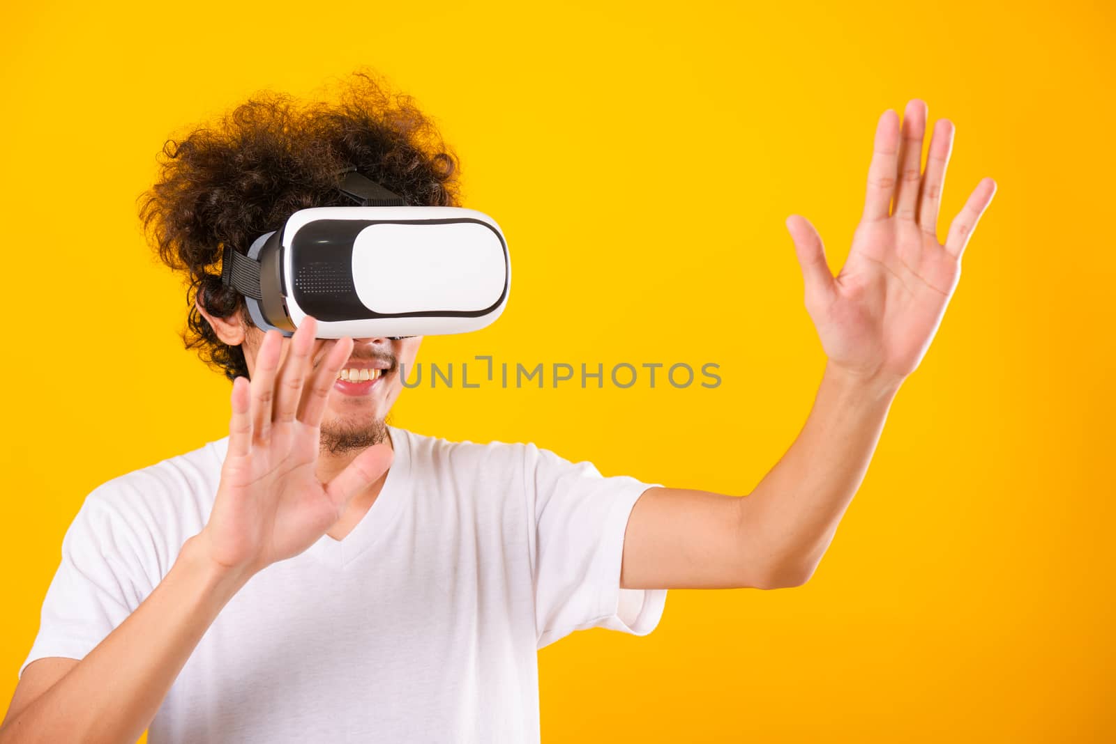 Asian handsome man with curly hair he using virtual reality headset or VR glass isolate on yellow background