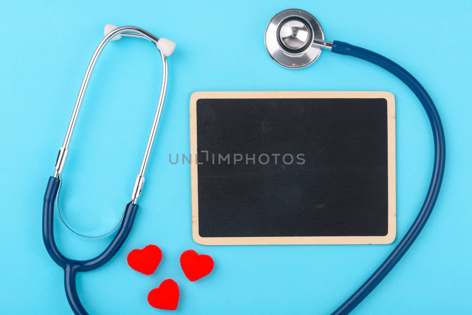 Doctor's Day concept, flat lay top view, stethoscope with red heart and black board on blue background, diagnosis of heart disease with copy space for text