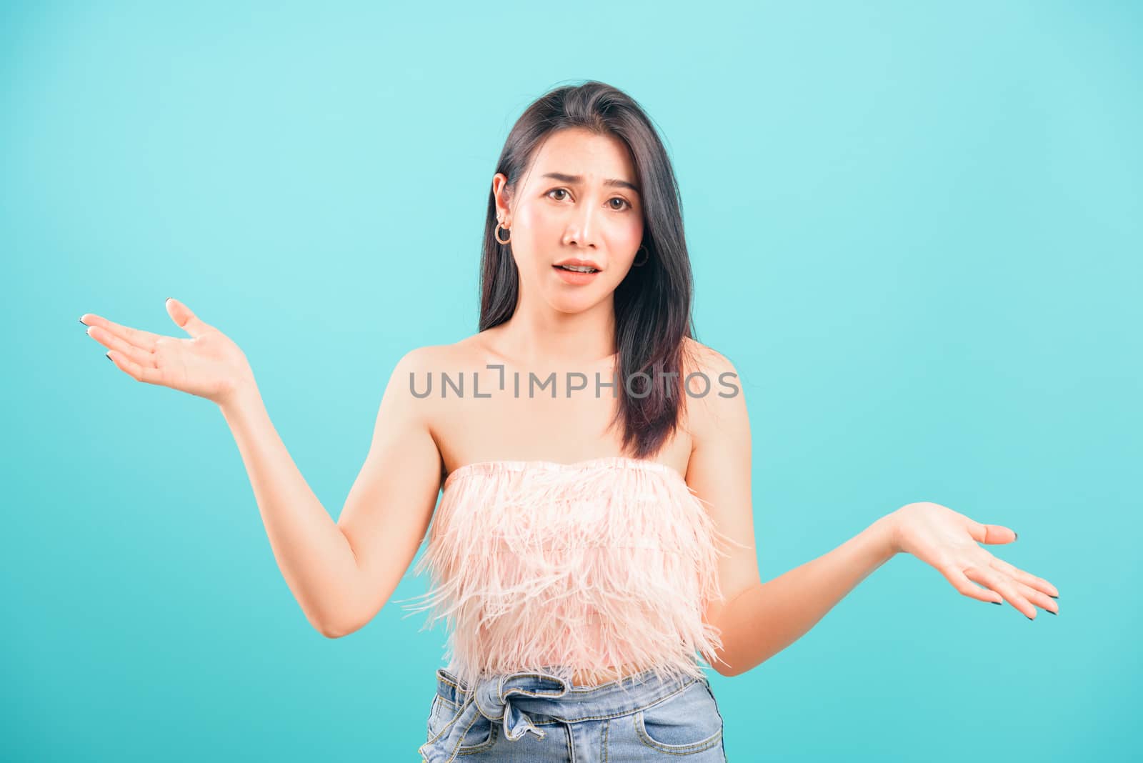 Asian beautiful woman her confused throwing hands aside on blue background, with copy space for text