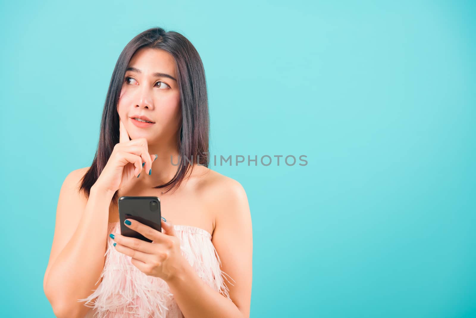 Portrait asian beautiful woman her holding mobile phone her confused and thinking on blue background, with copy space for text