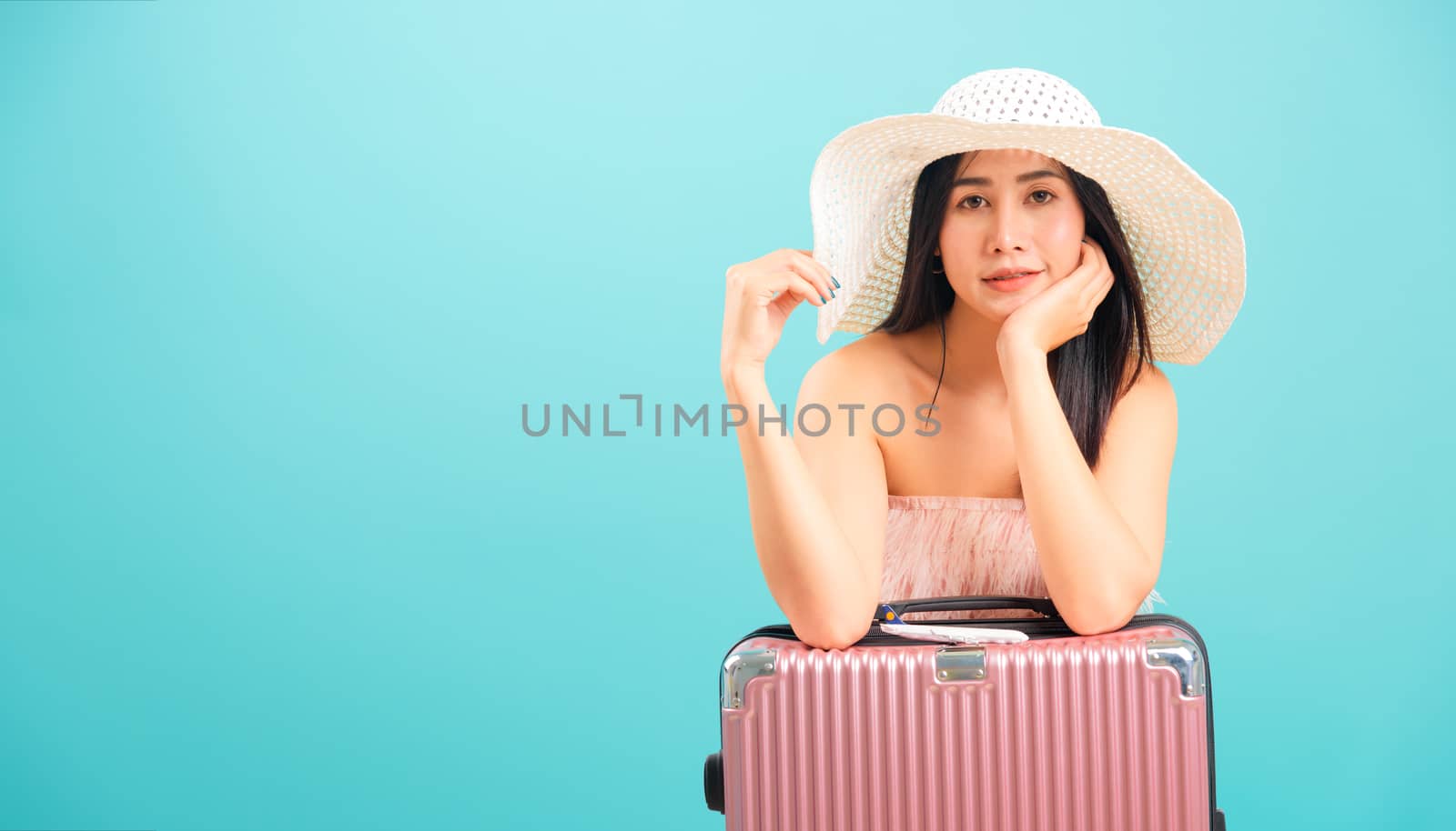 Portrait asian beautiful woman with hat her sitting with travel bag on weekends on blue background, with copy space for text