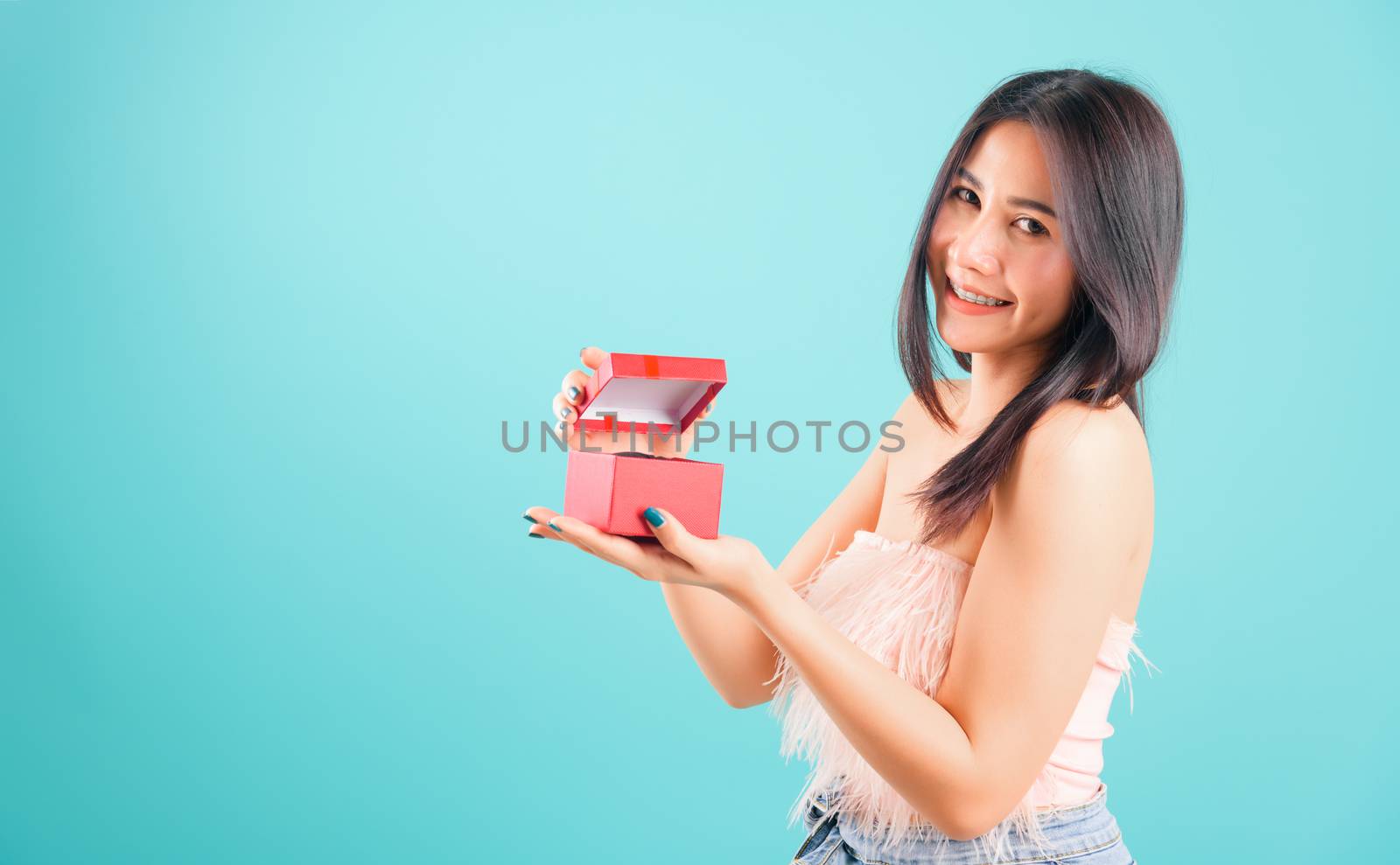 Portrait asian beautiful woman with hat her opening red gift box and her looking to gift box also on blue background, with copy space for text