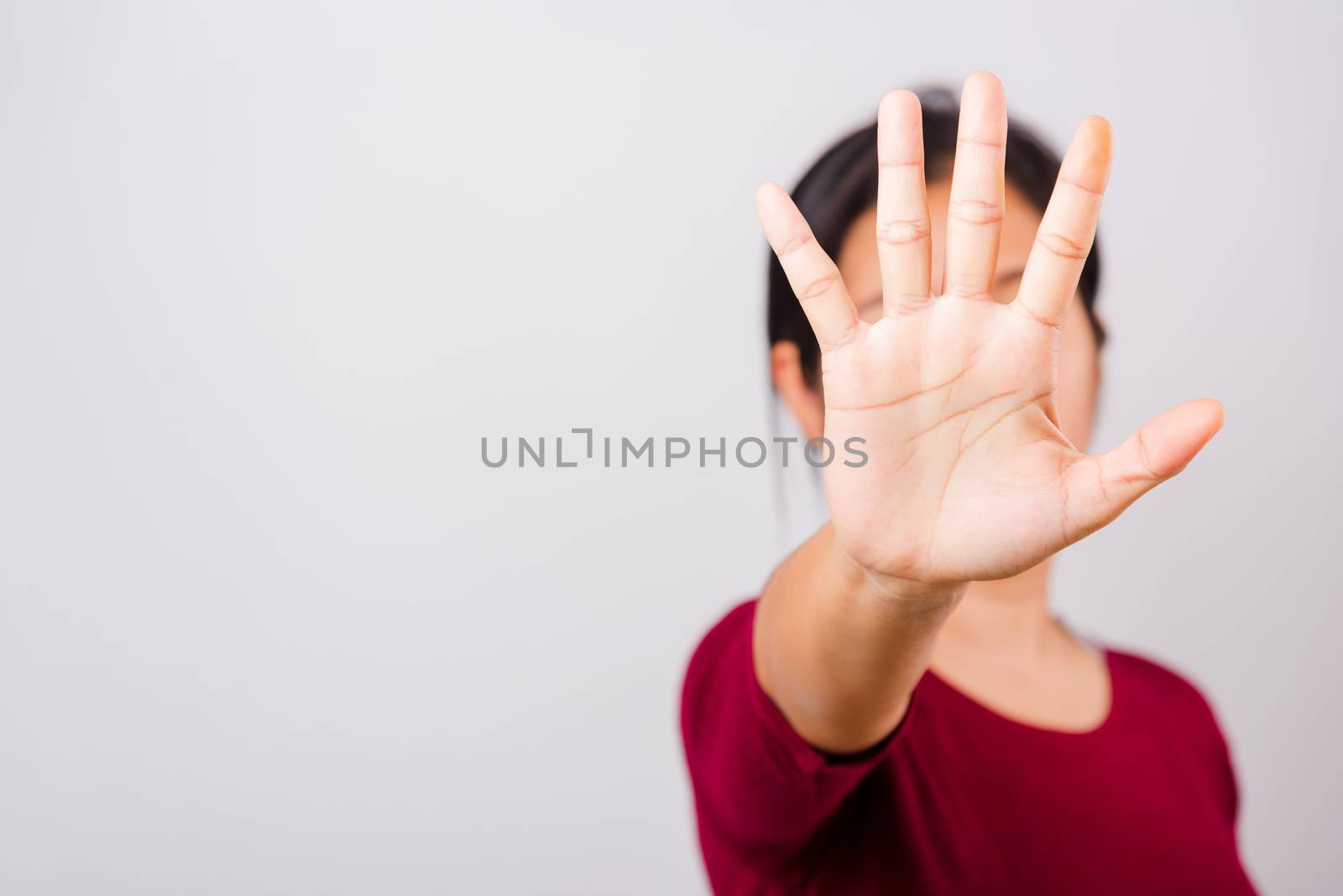Asian beautiful woman itching her outstretched hand showing stop gesture front face, focus on hand on white background with copy space