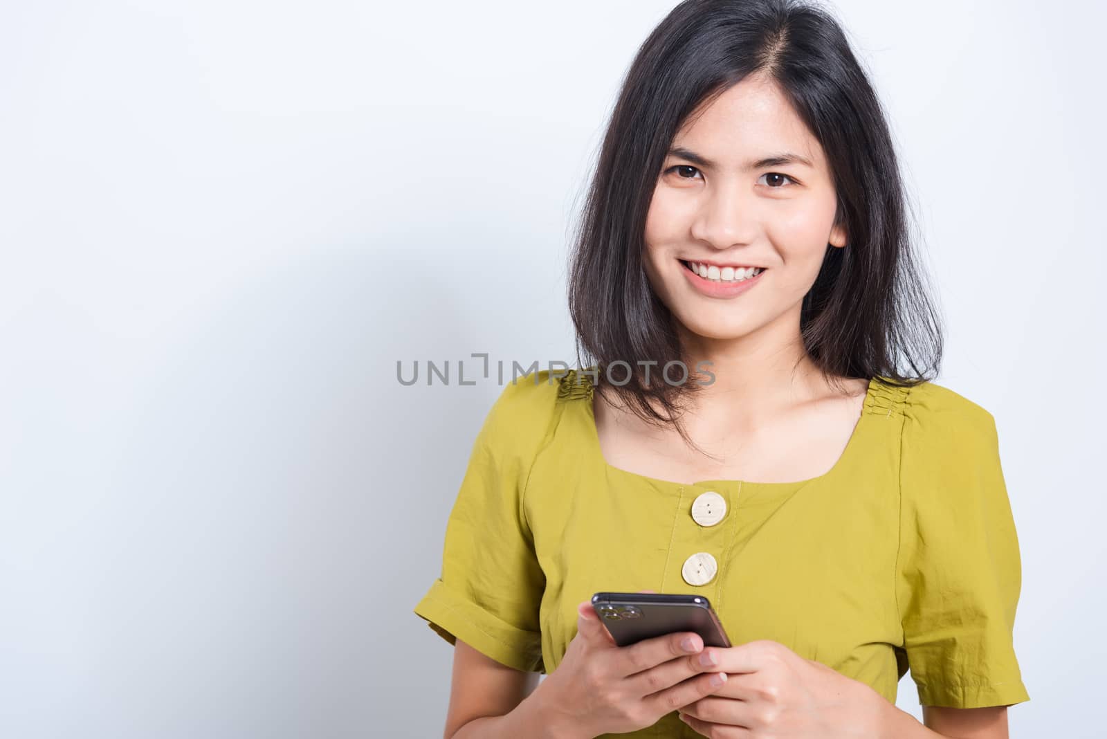 Portrait Asian beautiful happy young woman standing smile holding using mobile smart phone looking to camera, shoot the photo in a studio on a white background, There was copy space