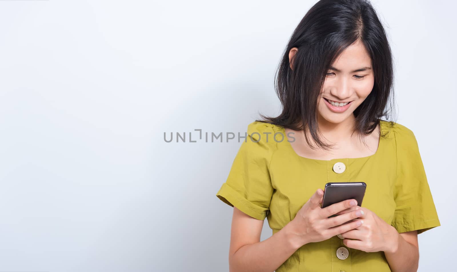 Portrait Asian beautiful happy young woman standing smile holding using mobile smart phone looking to smartphone, shoot the photo in a studio on a white background, There was copy space