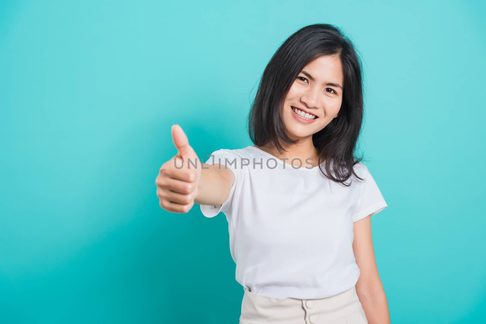 Portrait Asian beautiful young woman standing, She made finger thumbs up, Ok sign to agree and looking at camera, shoot photo in studio on blue background, There was copy space