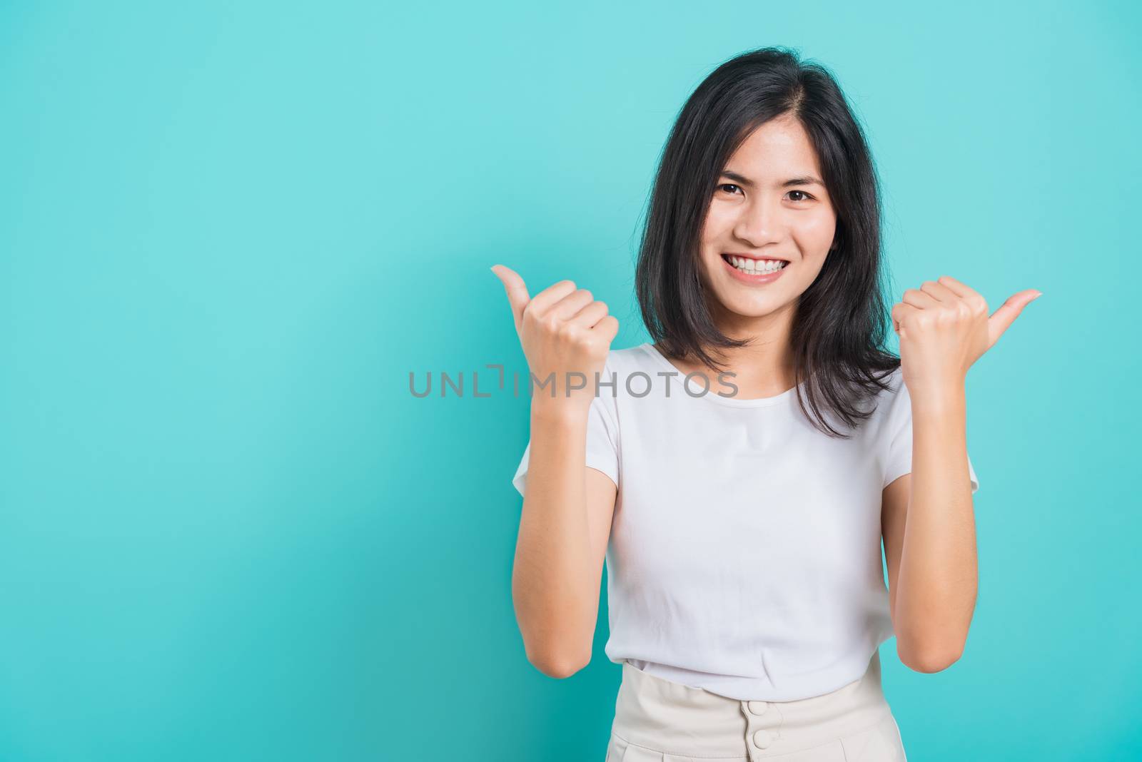 Portrait Asian beautiful happy young woman smile white teeth wear white t-shirt standing successful woman giving two thumbs up gesture, on a blue background with copy space