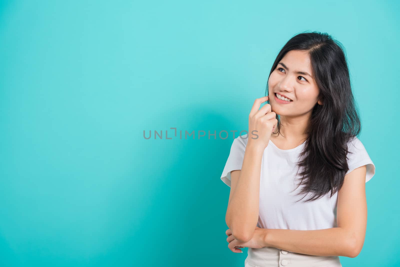 Portrait Asian beautiful happy young woman smile white teeth wear white t-shirt standing relaxed thinking about something about the question, on a blue background with copy space