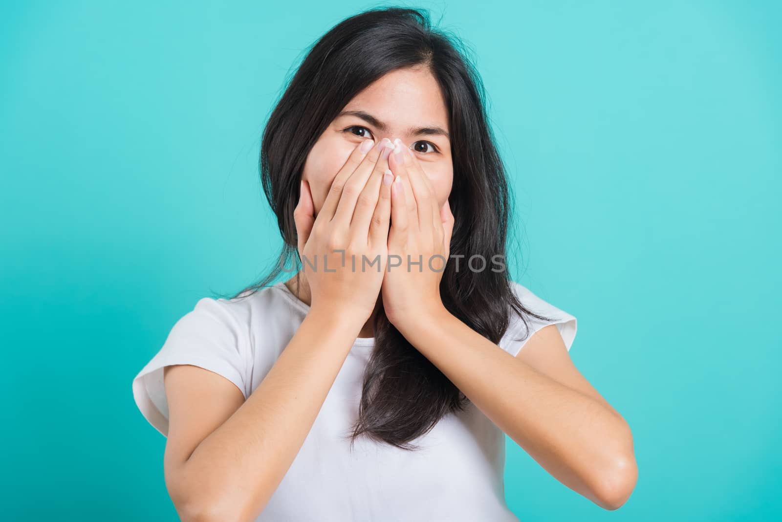 Portrait Asian beautiful happy young woman wear t-shirt happy excited laughs covering mouth with hands, on a blue background, with copy space