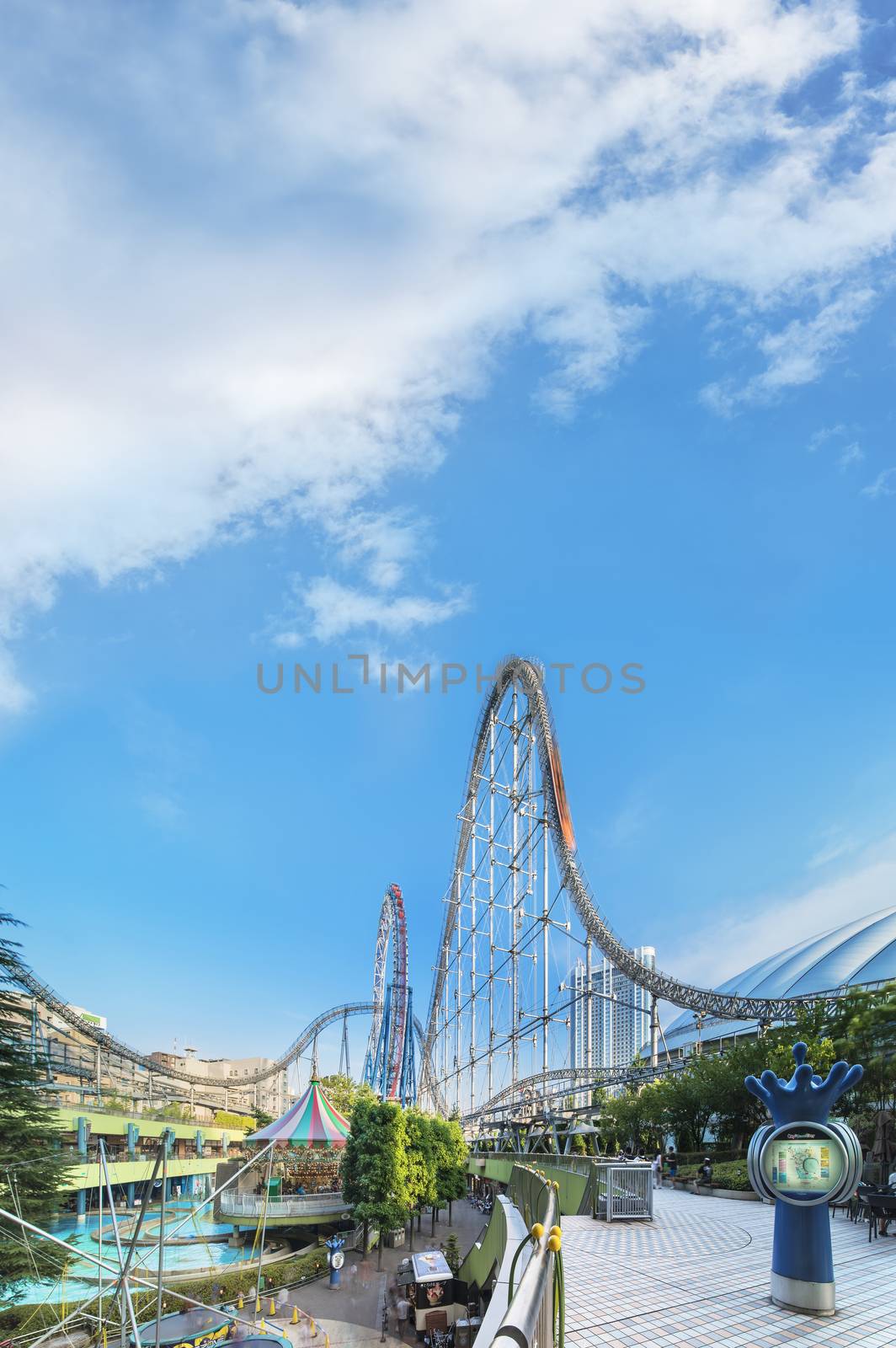 Laqua Tokyo Dome City Mall with its impressive roller coaster integrated in the gallery of its shopping center with a carousel  and water coaster under the summer blue sky.