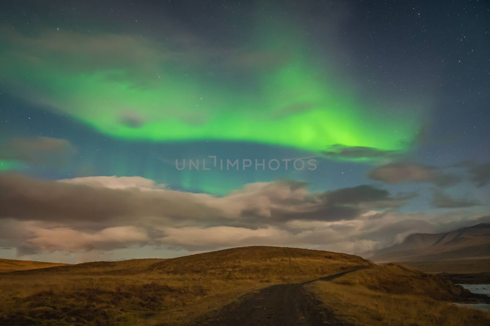 Aurora Borealis in Iceland northern lights bright beams rising in green beams over hiking path by MXW_Stock