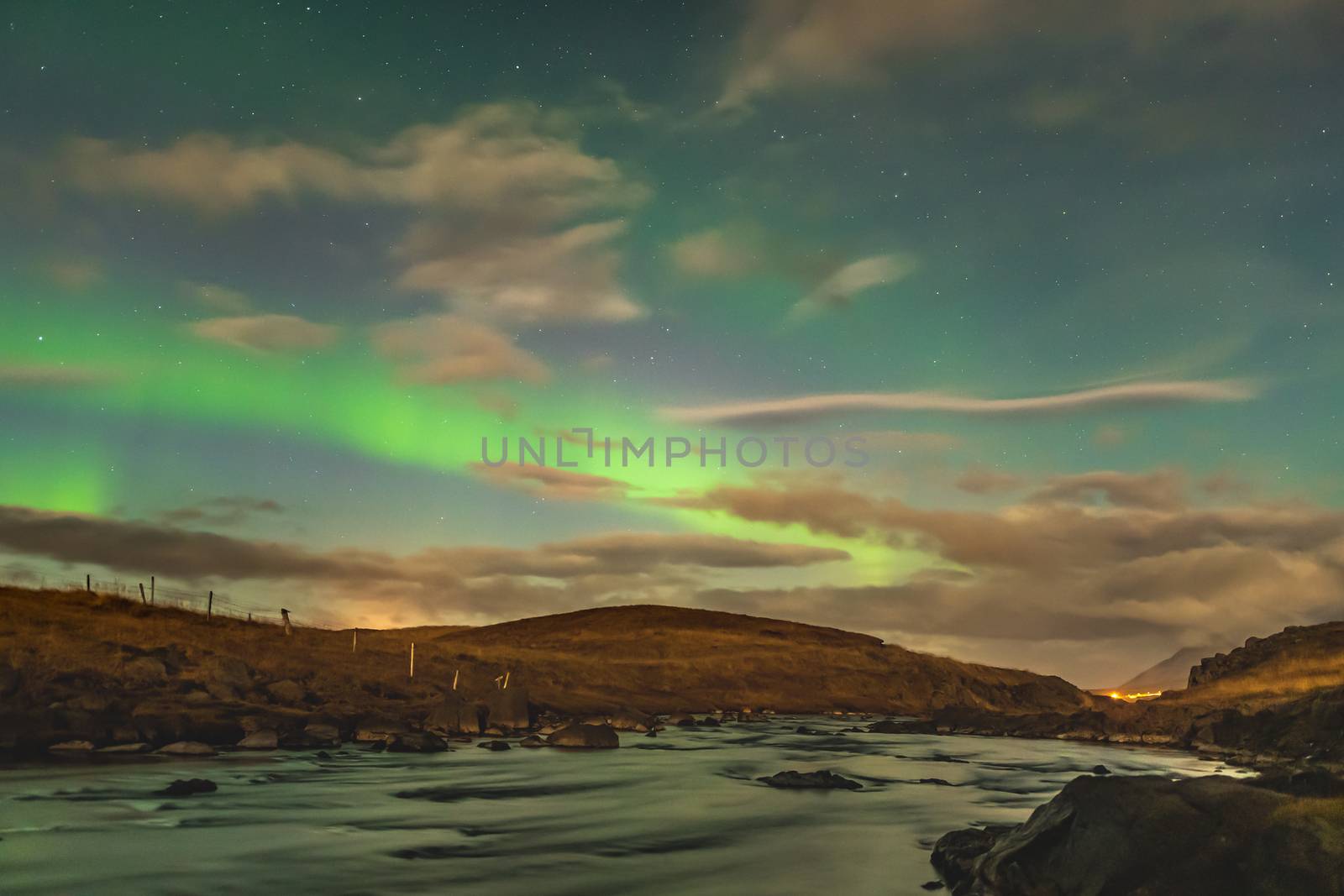 Aurora Borealis in Iceland northern lights bright beams rising in green beams reflecting in river by MXW_Stock