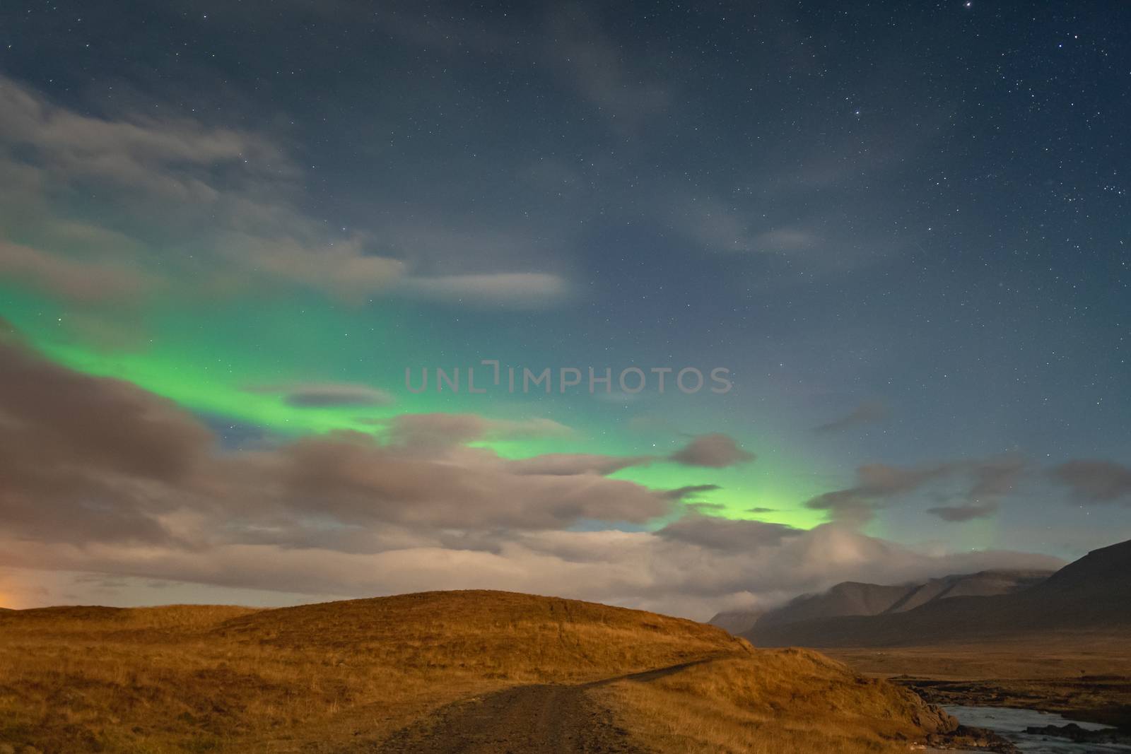 Aurora Borealis in Iceland northern lights bright stripe in sky during full moon night by MXW_Stock