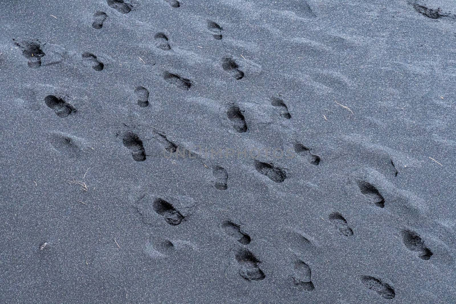 Black sand footsteps on dark sand in volcanic iceland