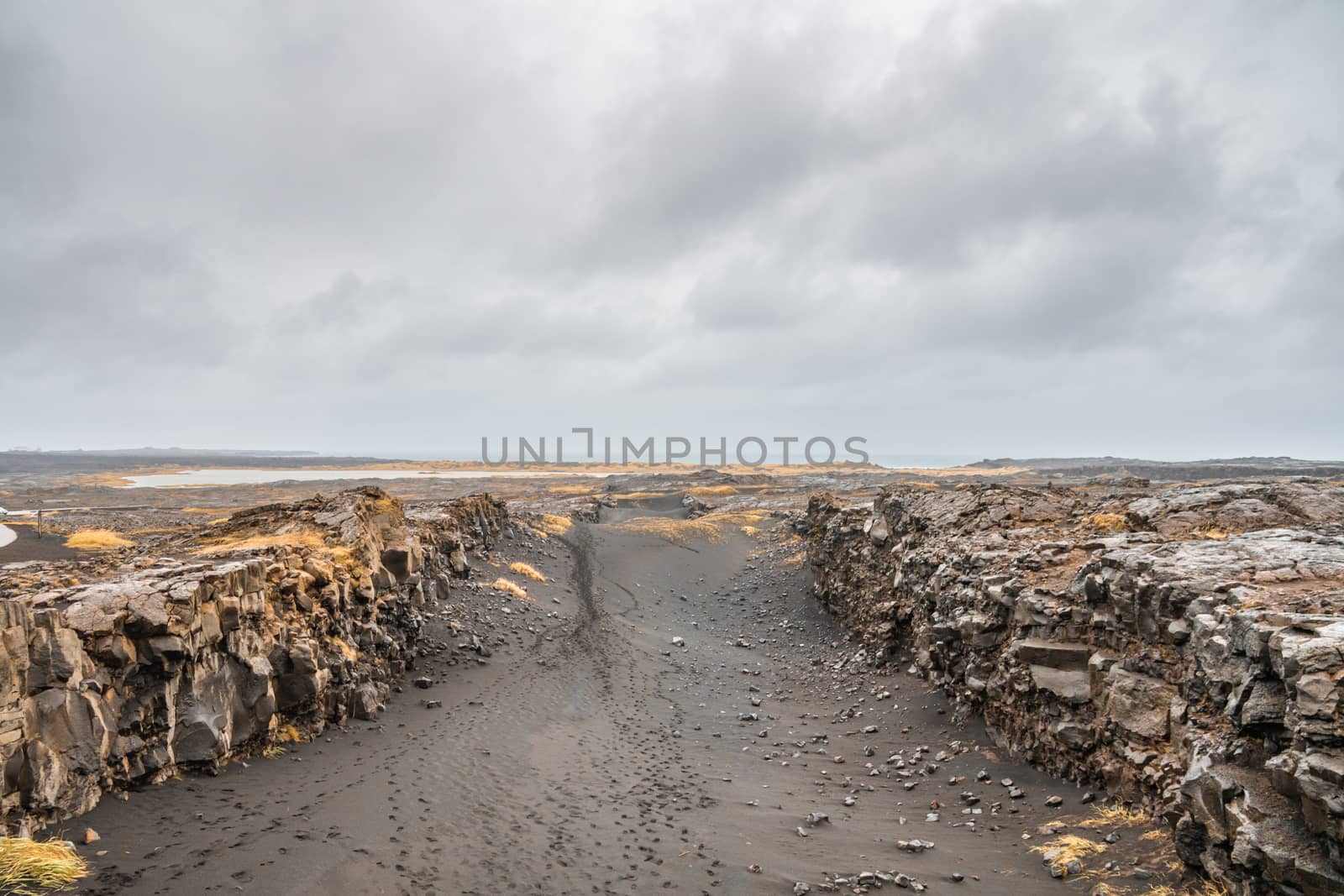 Bridge between continents in Iceland black sand in canyon during stormy weather by MXW_Stock