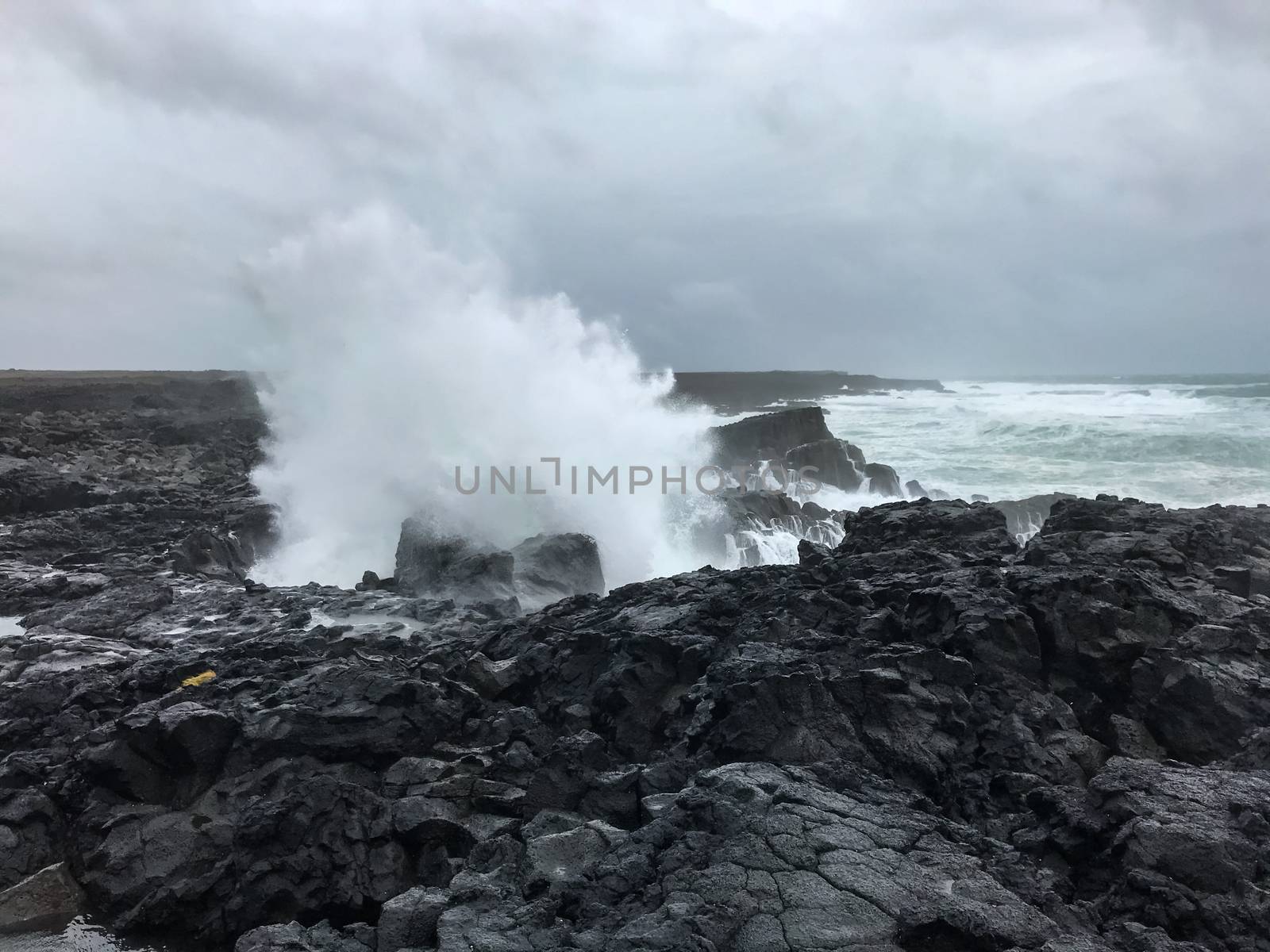 Brimketill lava rock pool in Iceland spray of huge wave by MXW_Stock