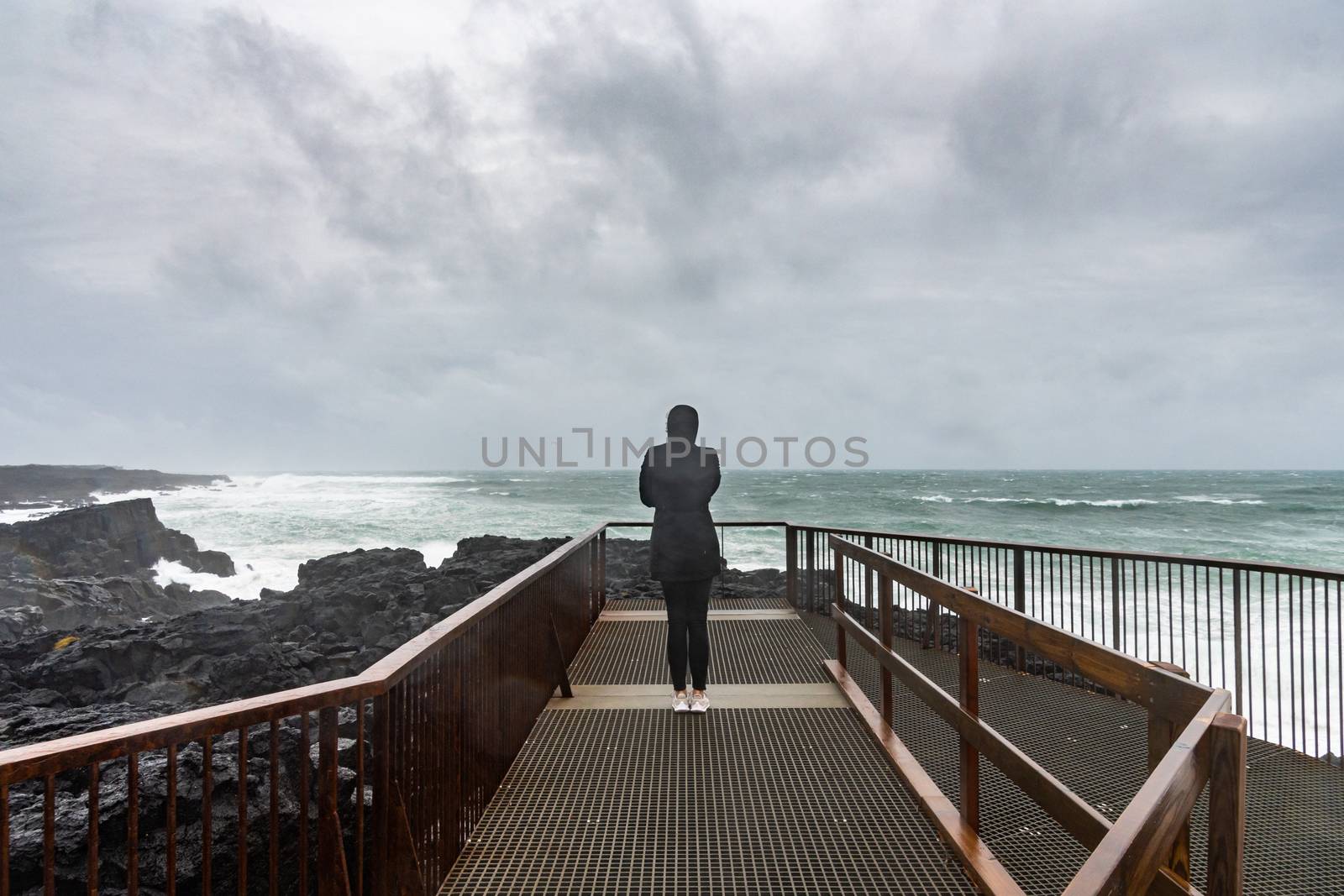Brimketill lava rock pool Iceland silhouette of person in front of stormy ocean