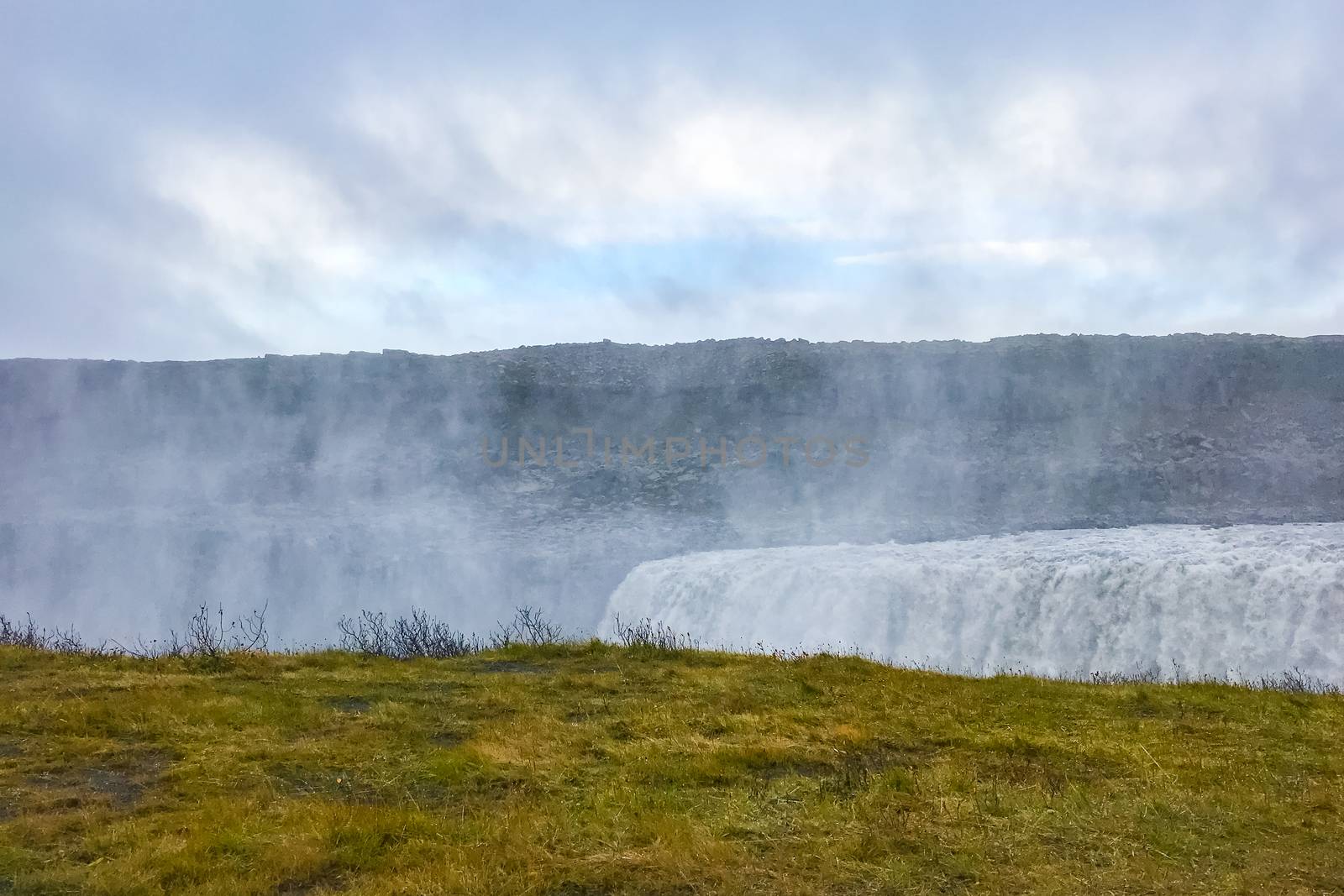 Dettifoss waterfall in Iceland creating big clouds of spray during cloudy day