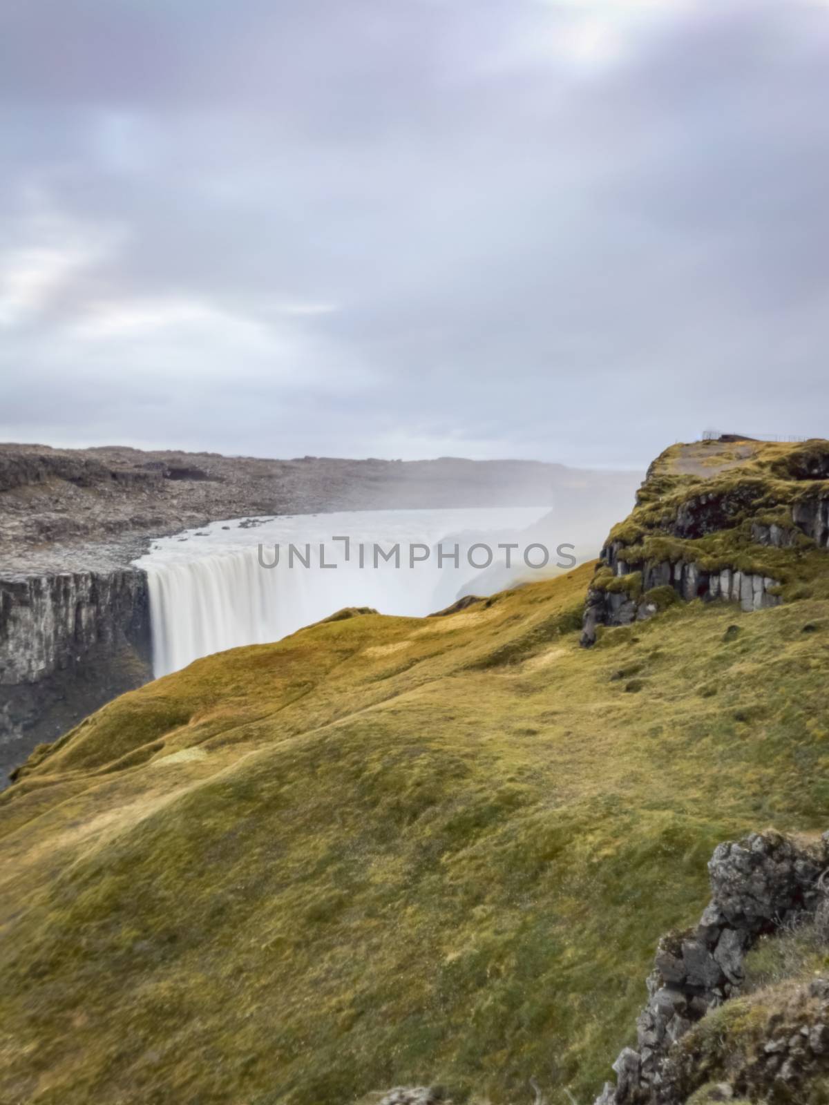 Dettifoss waterfall in Iceland long exposure of water falling over the edge behind thick layer of grass land