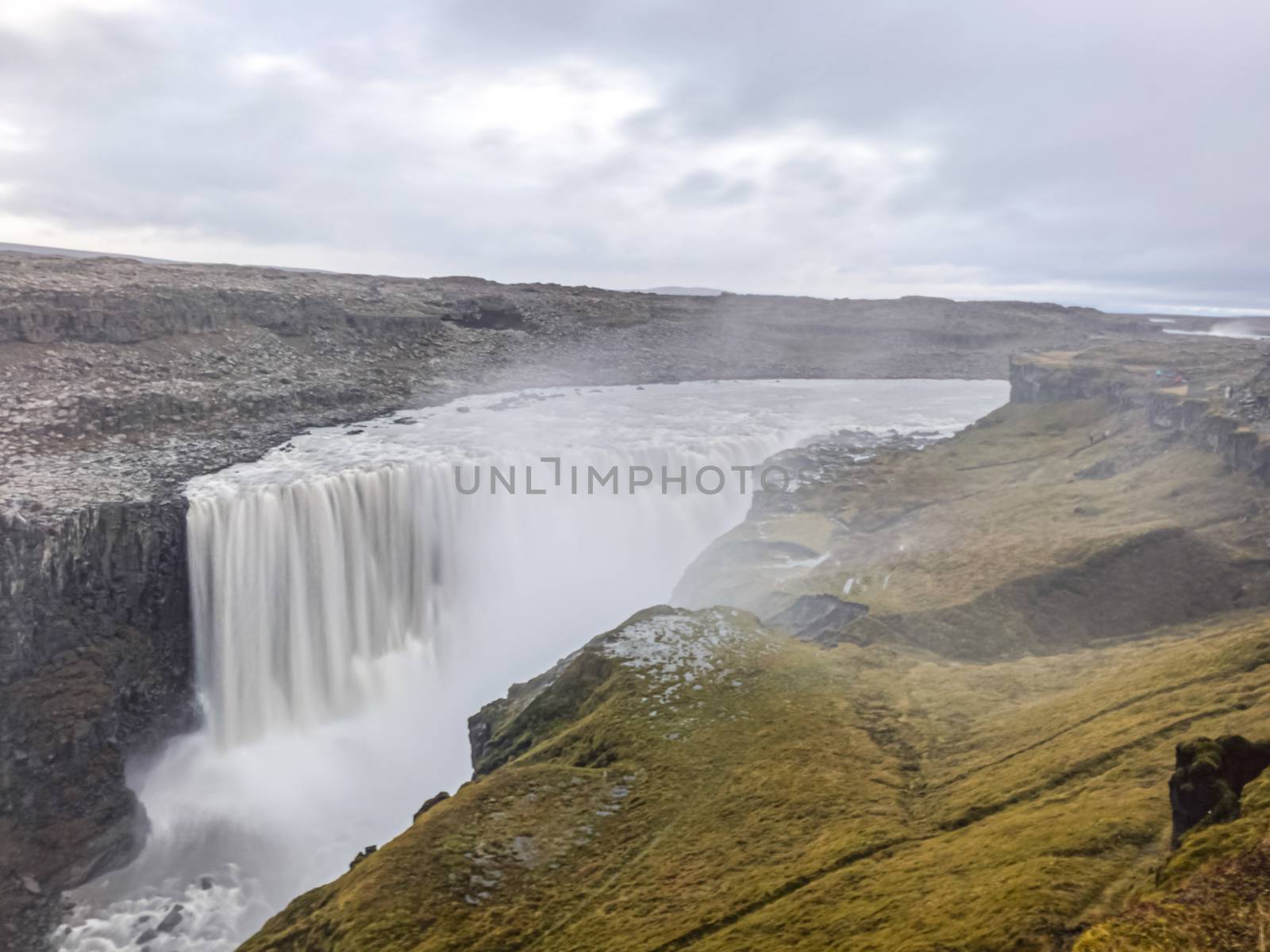 Dettifoss waterfall in Iceland long exposure of water falling over the edge creating massive clouds of spray by MXW_Stock