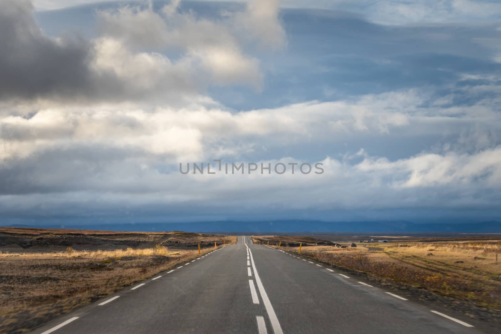 Empty road in Iceland driving in sunshine towards bad weather in the Highlands by MXW_Stock