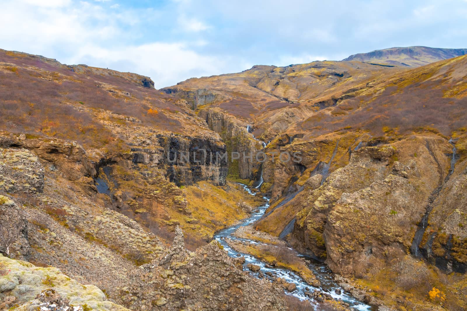 Glymur waterfall in Iceland gorge behind fall cutting through colorful autumn landscape by MXW_Stock