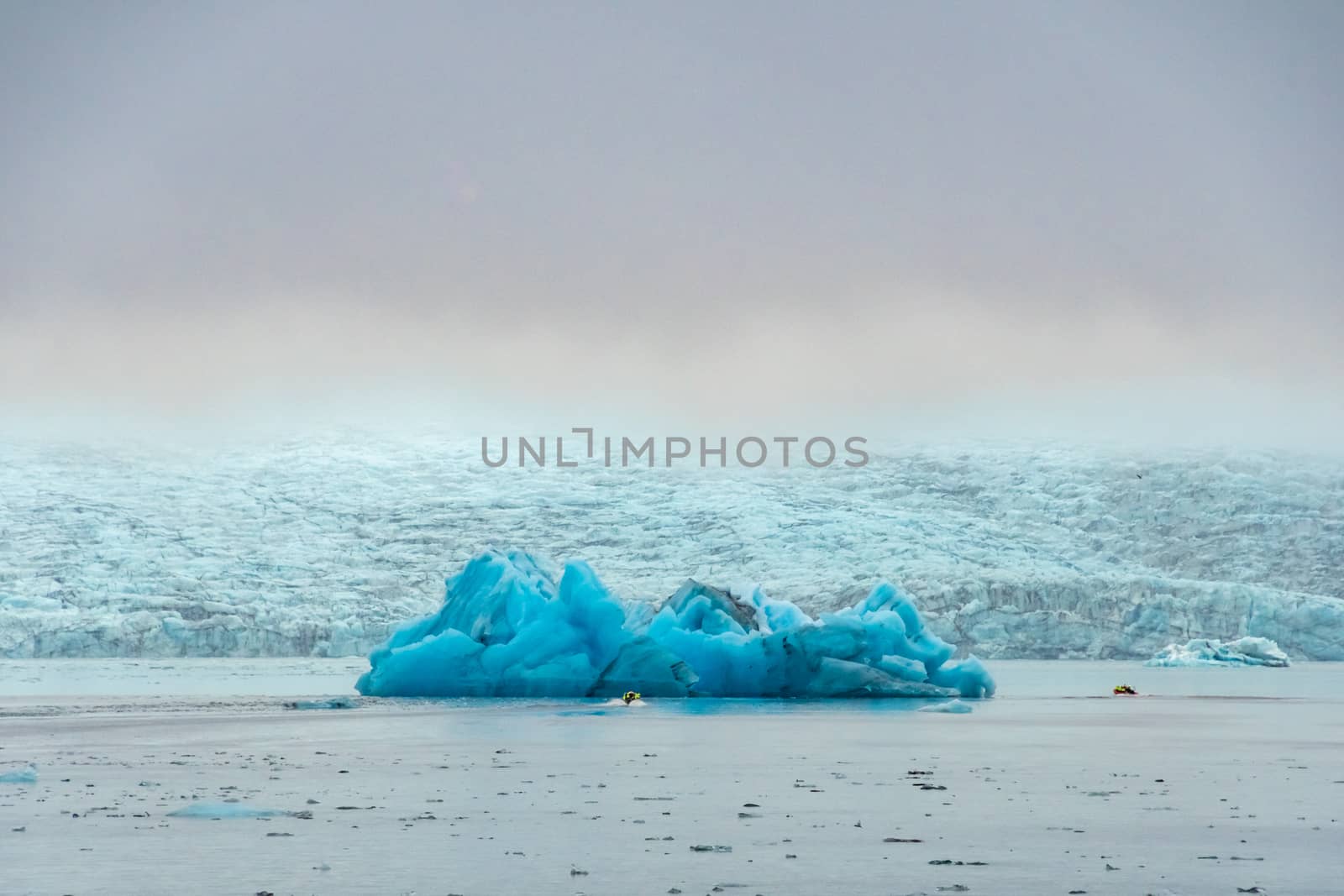 Joekulsarlon Glacier Lagoon motor boat in front of giant iceberg in deep blue color