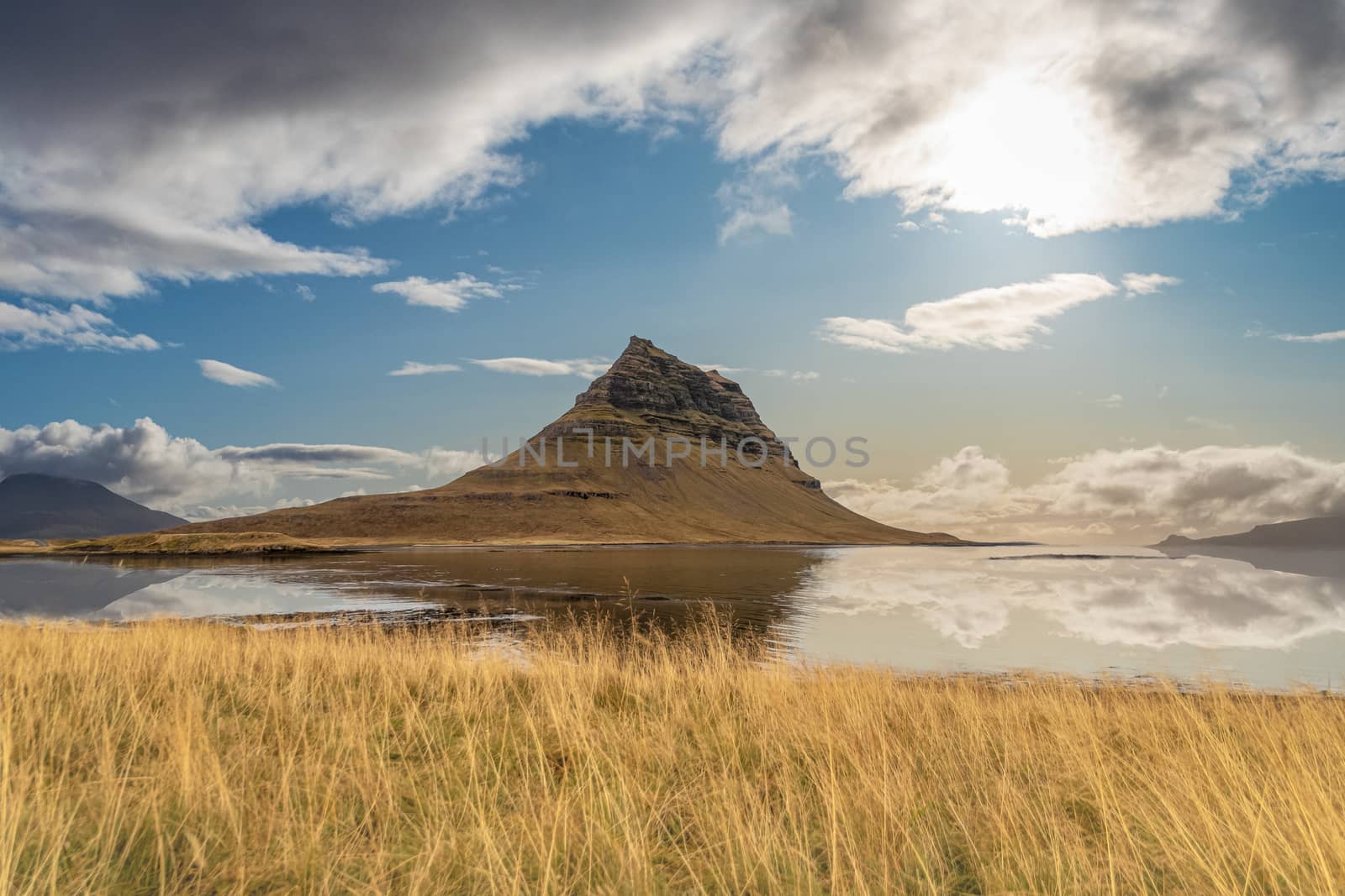 Kirkjufell in Iceland famous mountain reflecting in lake during calm and sunny day