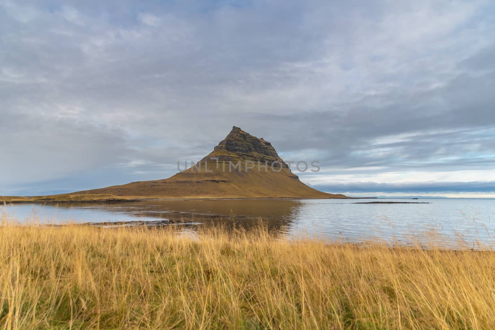 Kirkjufell in Iceland famous mountain reflecting in flat lake during stormy day