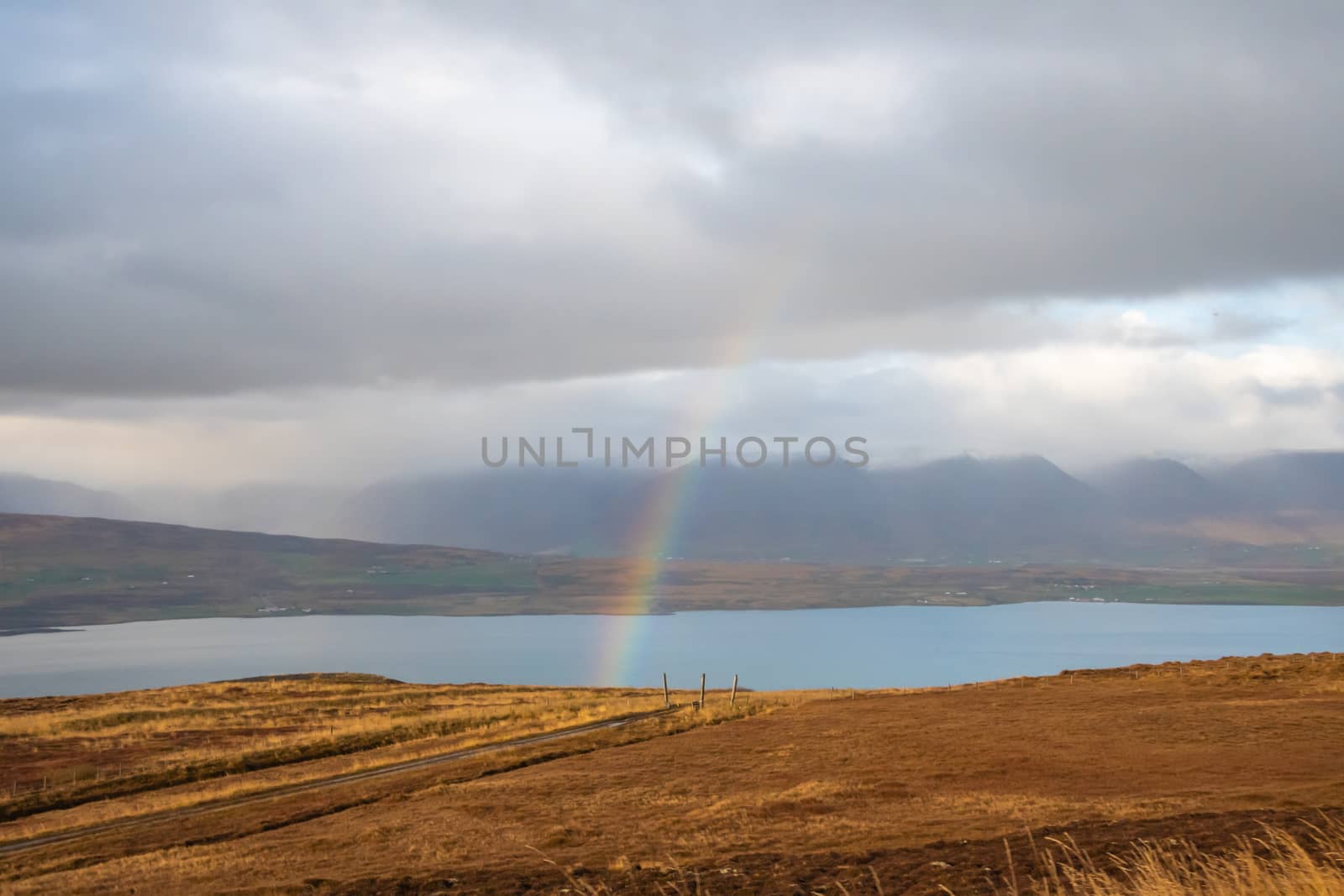 Mountain pass towards Akureyri in Iceland rainbow forming over fjord by MXW_Stock