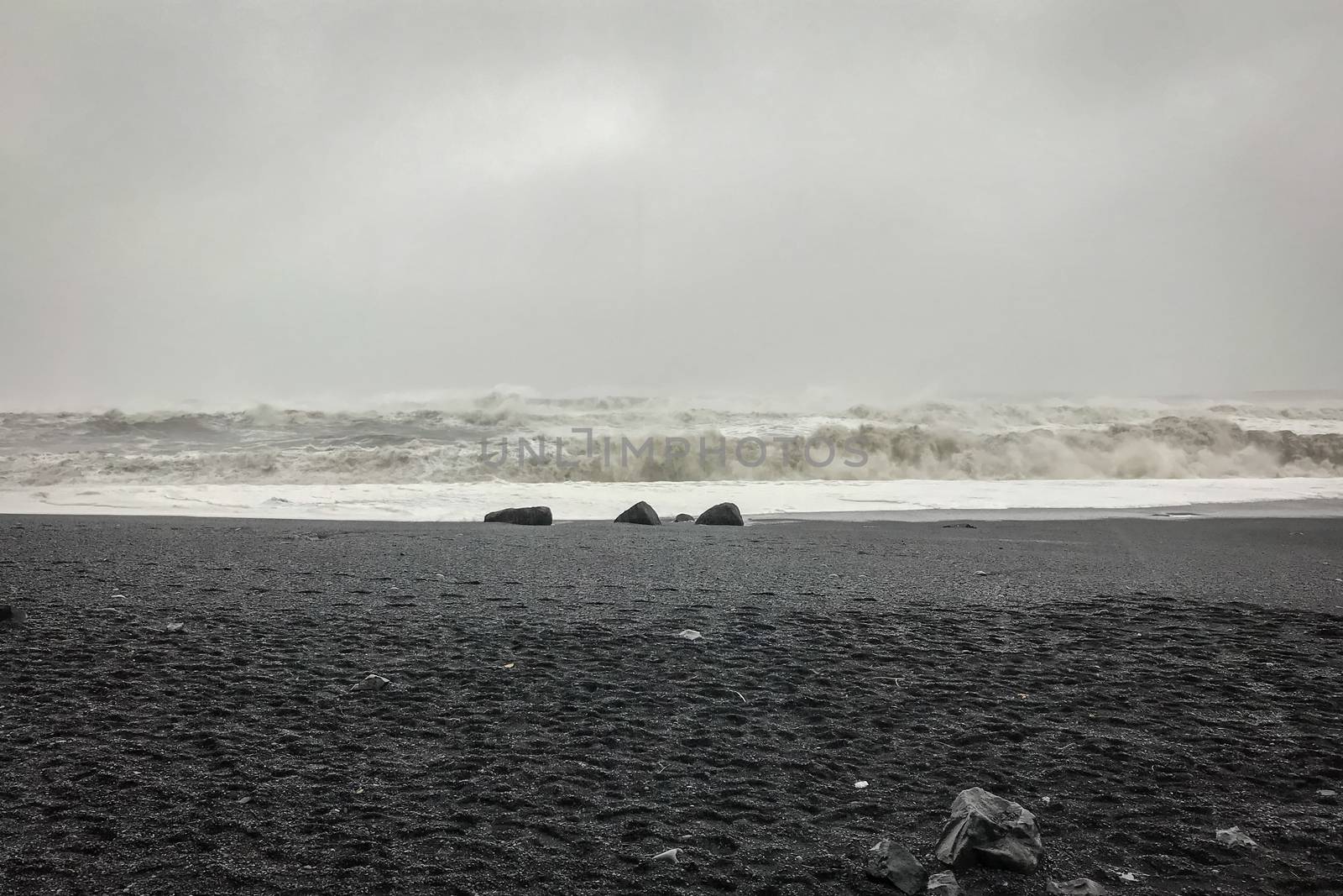 Reynisfjara Beach next to Reynisdrangar huge waves hitting beach during stormy weather and heavy rainfall by MXW_Stock