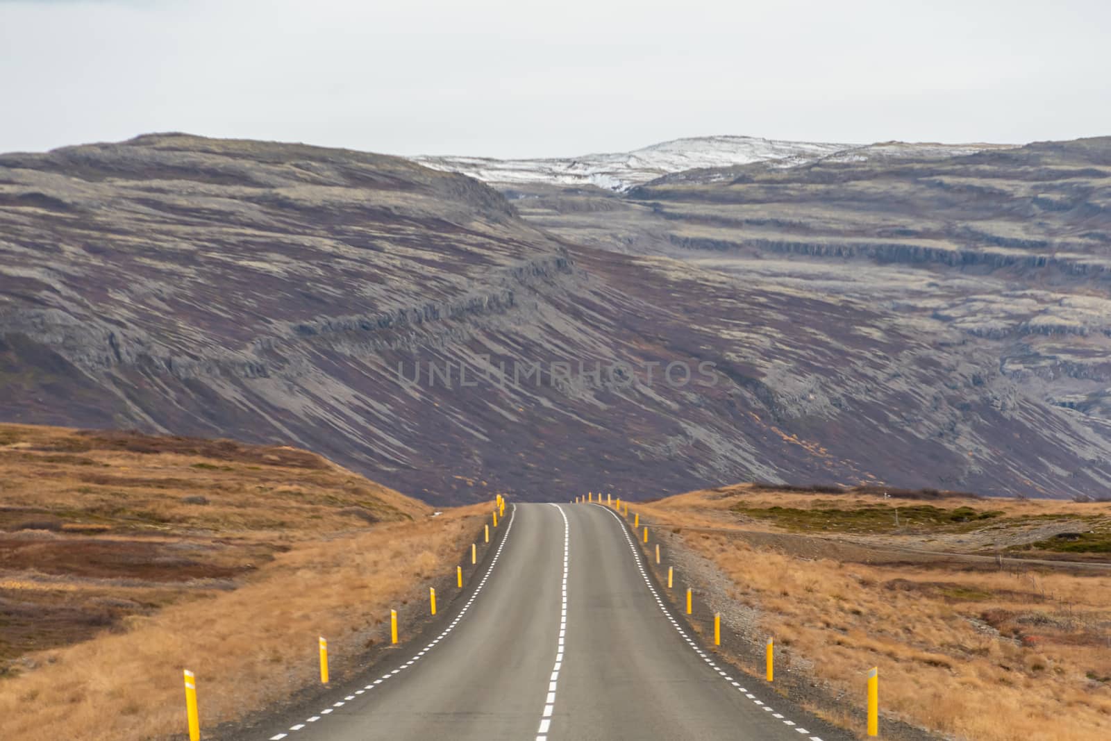 Roadtrip in Iceland empty road over sparse mountain landscape in western iceland by MXW_Stock