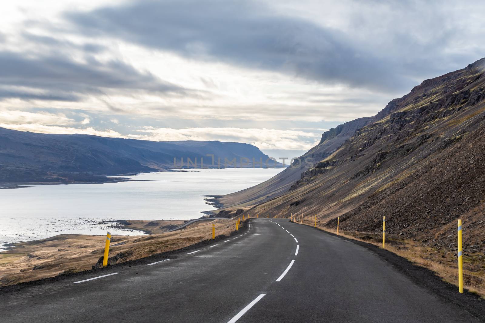 Roadtrip in Iceland steep descent down into fjord between black mountains by MXW_Stock