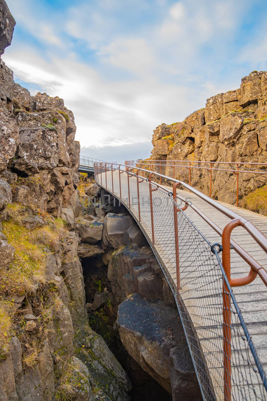 Thingvellir National Park in Iceland during sunny weather hiking path bridging over canyon by MXW_Stock