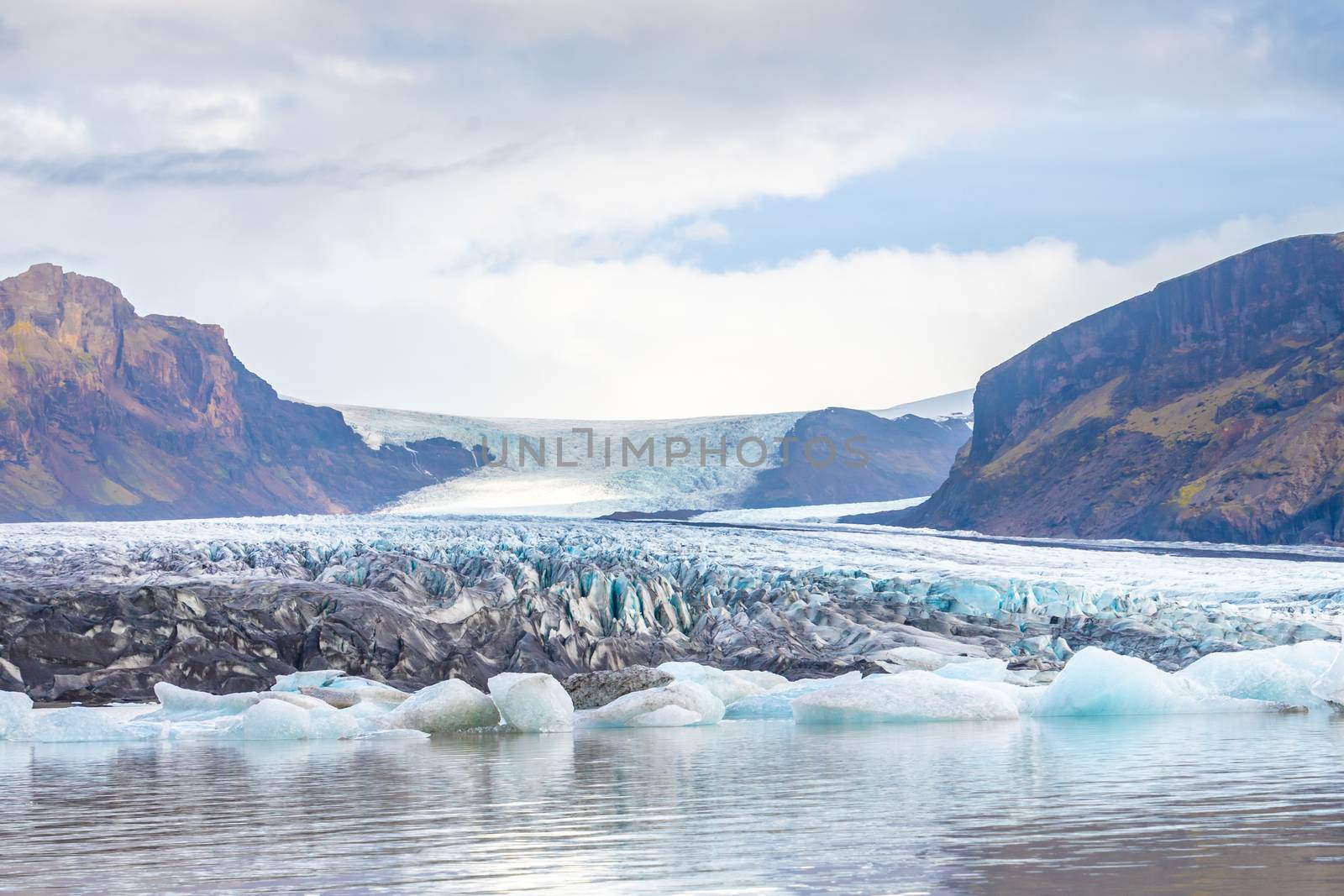 Vatnajoekull glacier in Iceland blue and ash colored ice melting into glacier sea