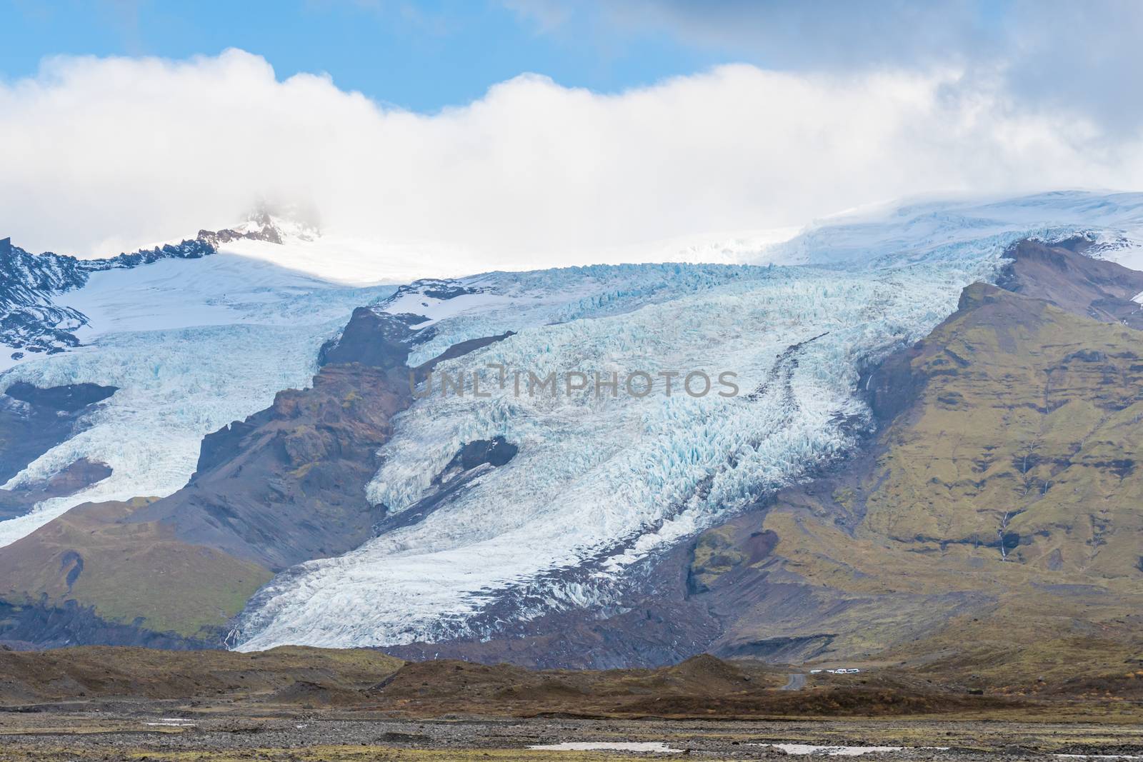Vatnajoekull glacier in Iceland spiky crevasse in deep blue color flowing down the mountain by MXW_Stock