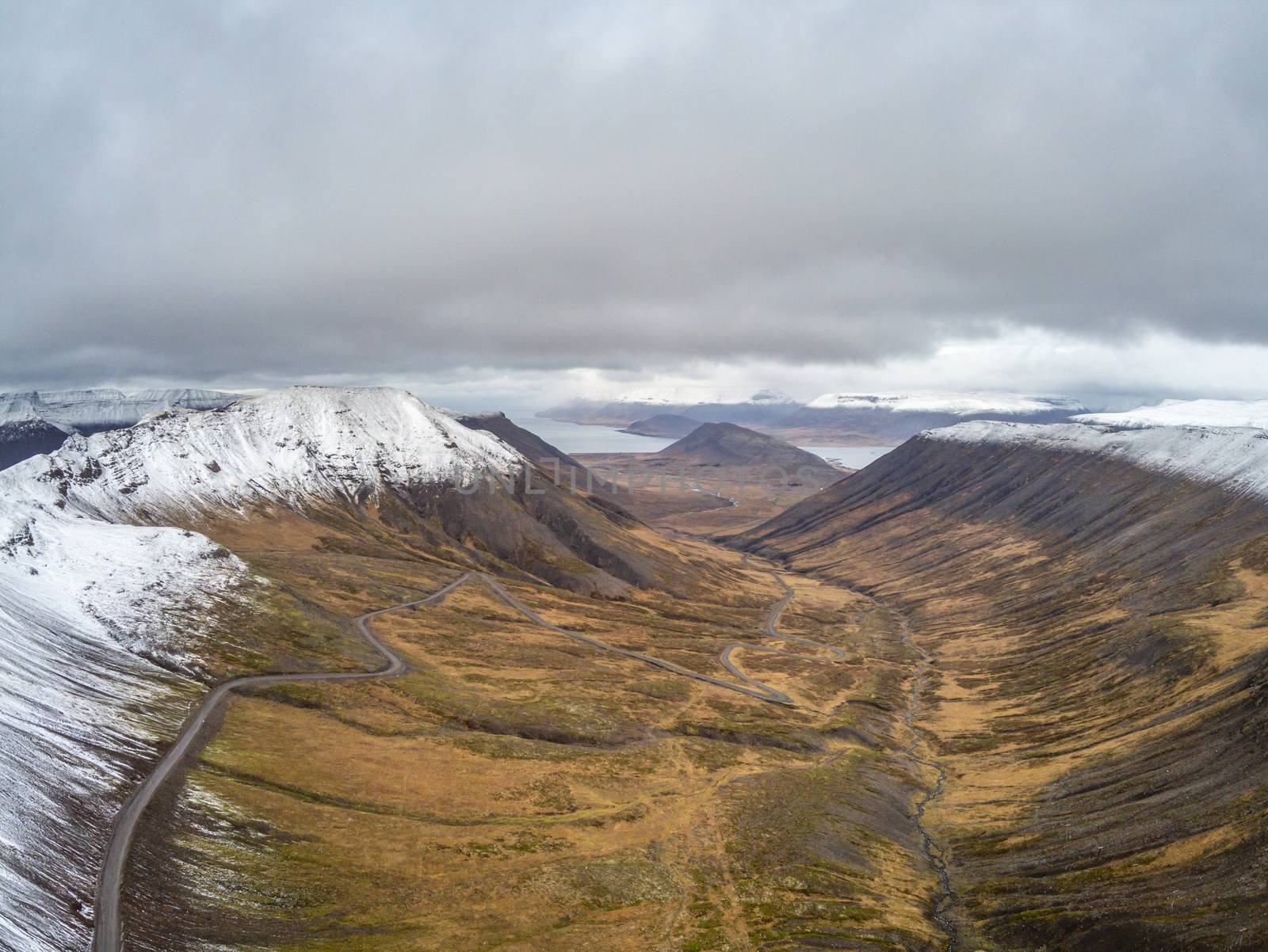 West fjords of Iceland aerial photo of mountain pass leading down in valley beyond snow line