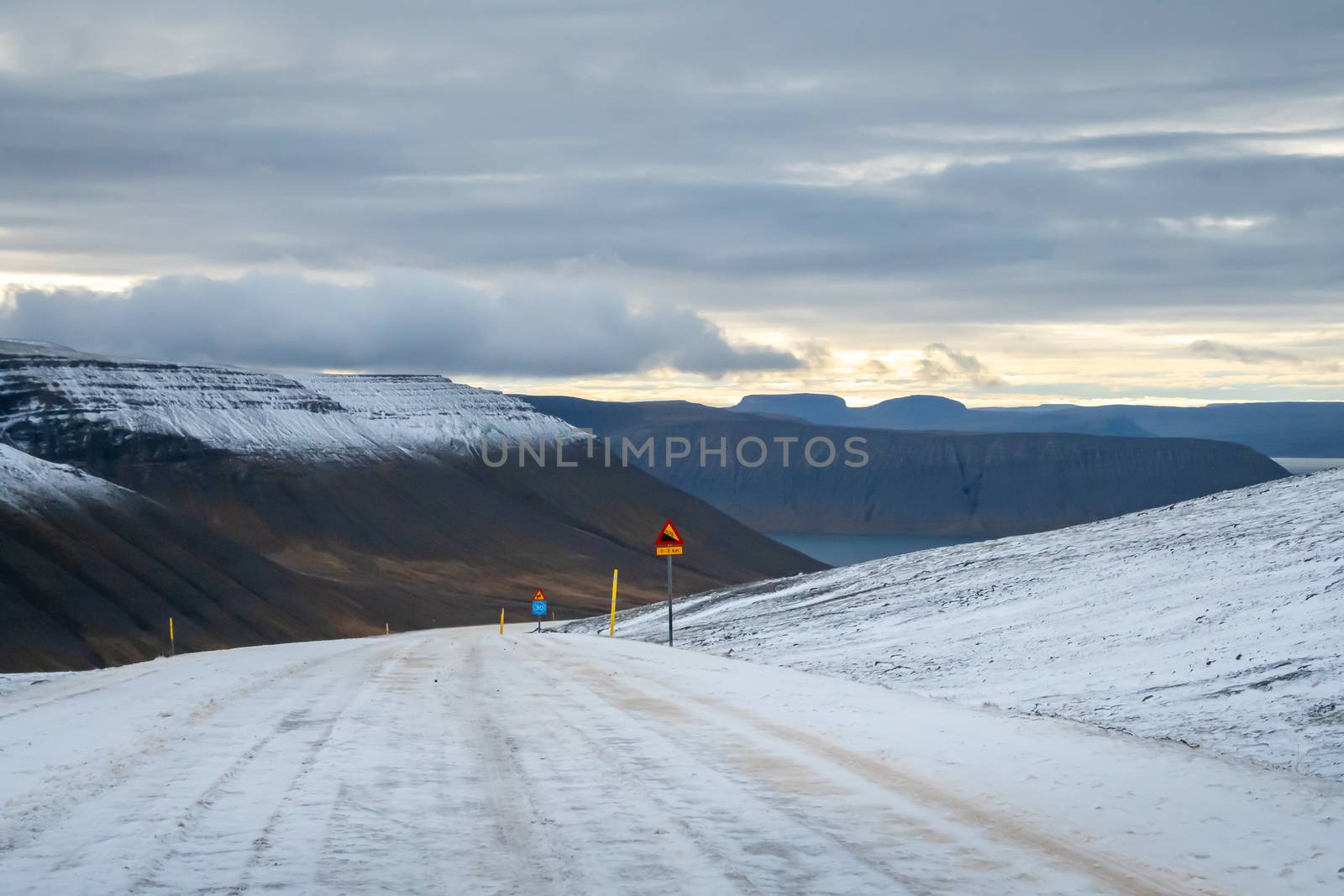 West fjords of Iceland snow covered mountain pass steep decline down into fjord