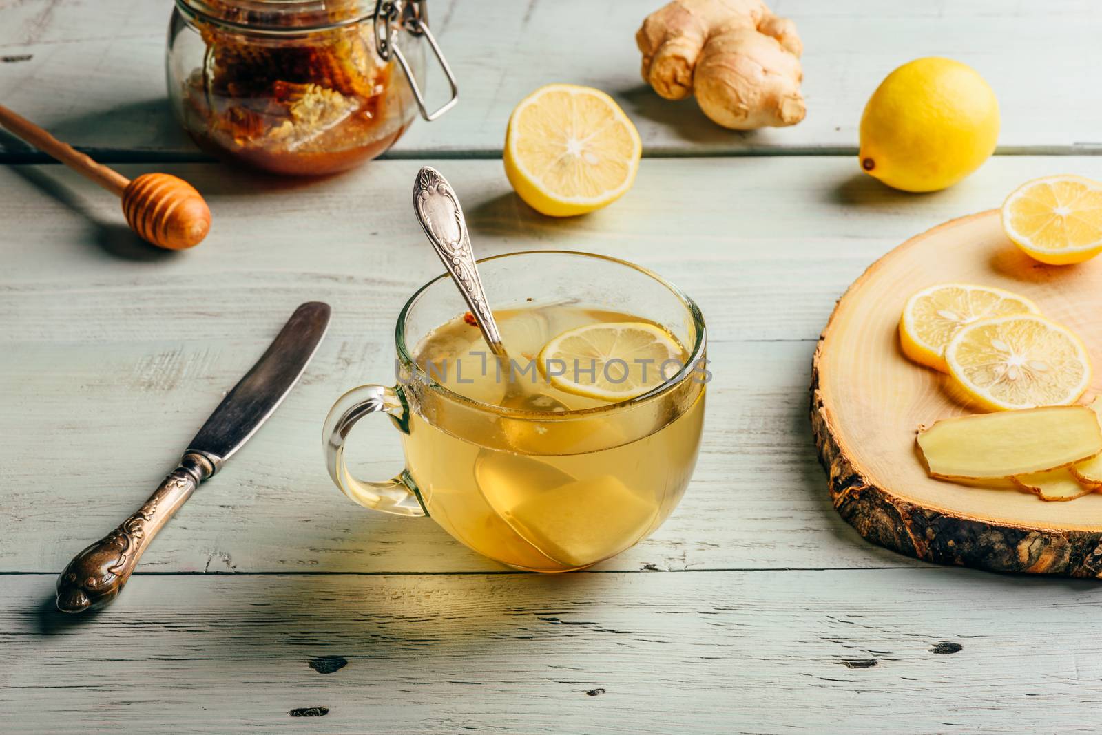 Cup of tea with lemon, honey and ginger over wooden surface