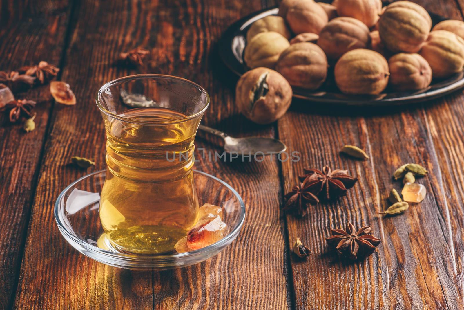 Oriental tea with star anise, cardamom and dried lime in armudu glass over wooden surface