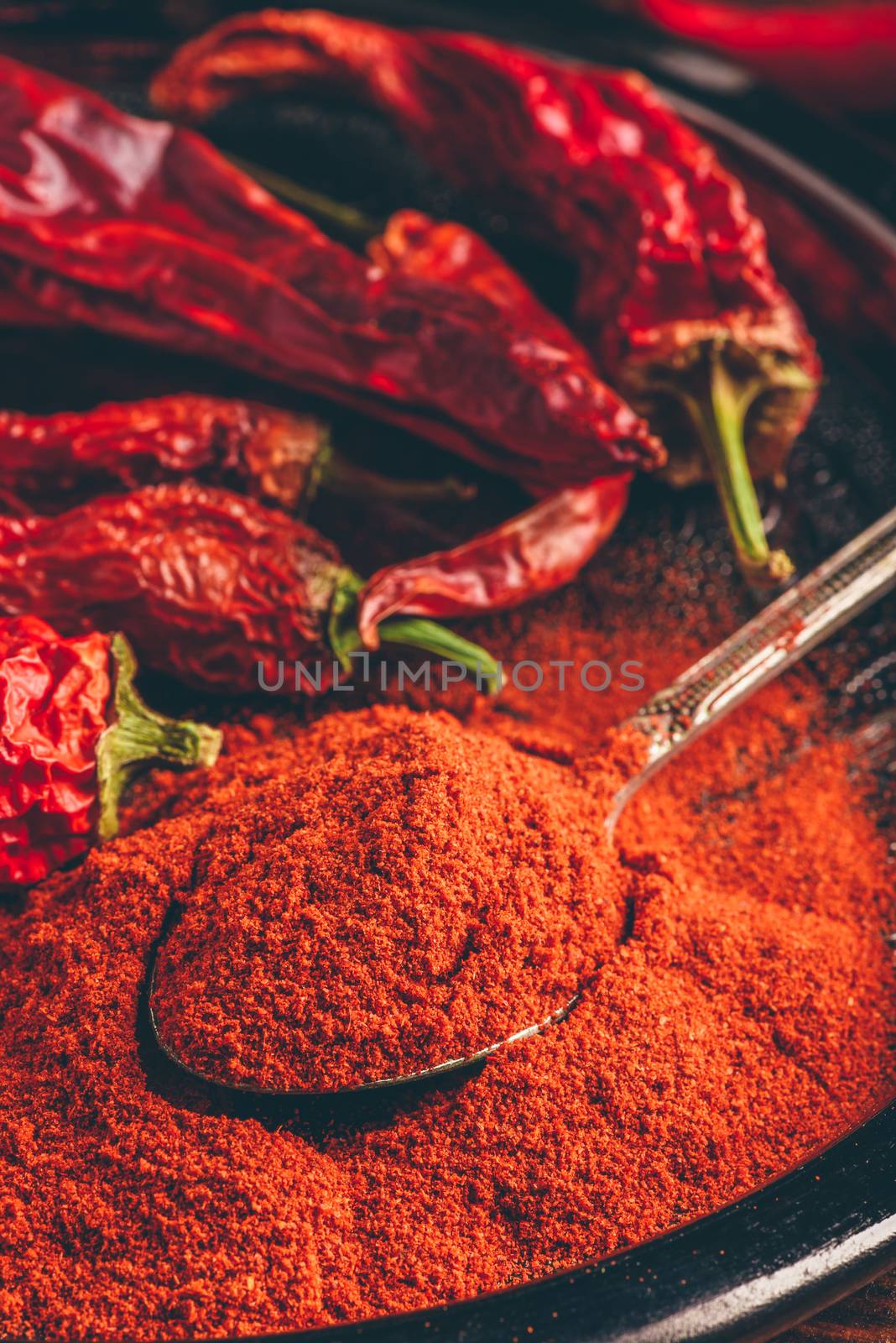 Spoonful of ground red chili pepper with dried peppers