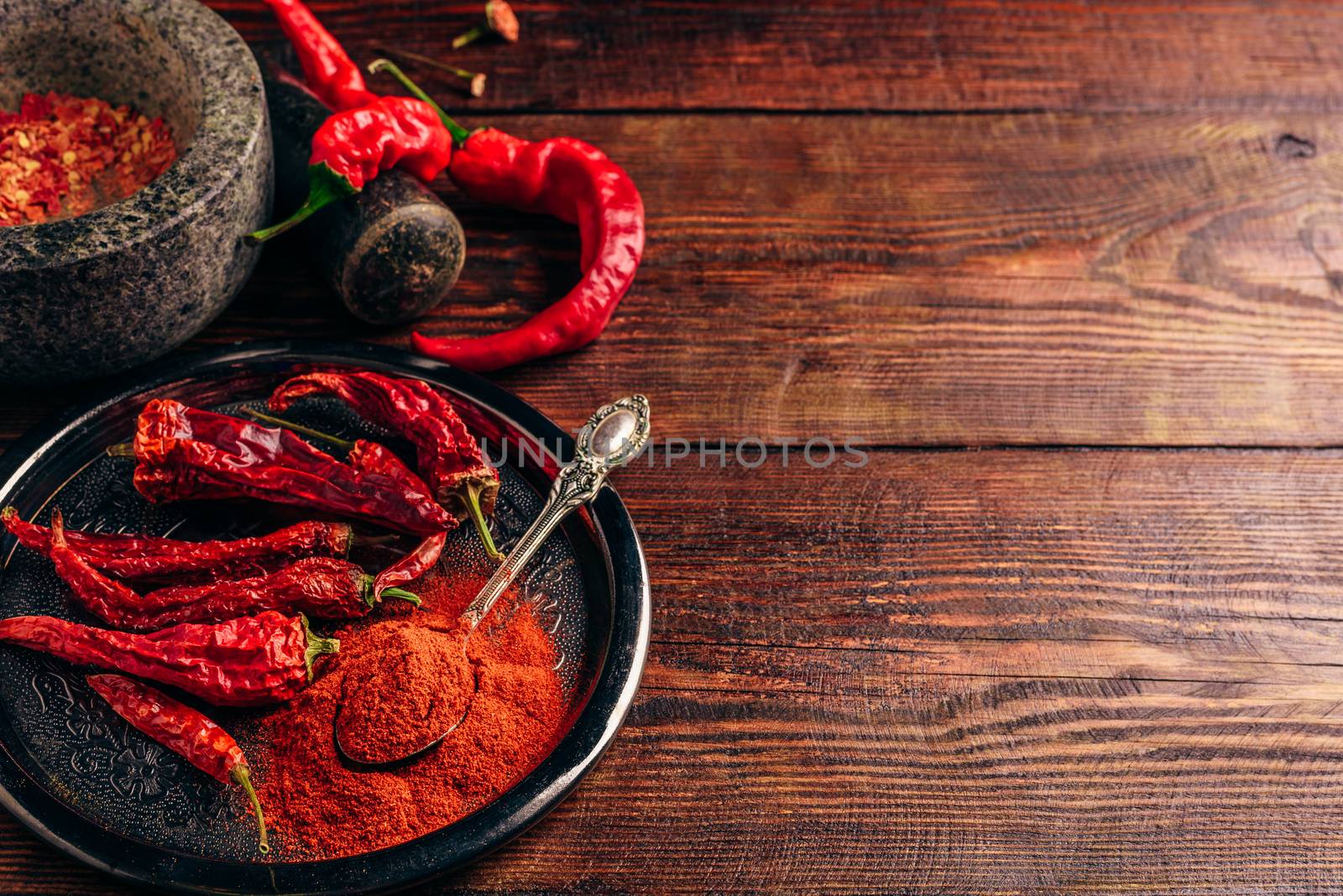 Fresh, dried and ground red chili peppers over wooden surface. Copy space