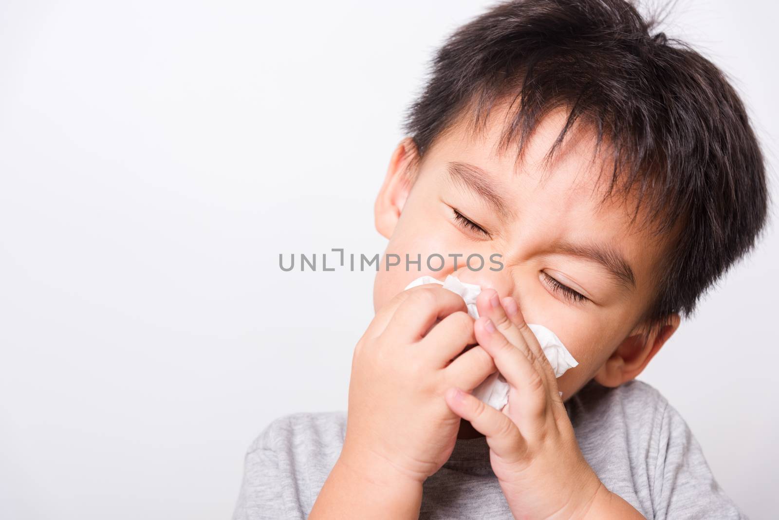 Closeup Asian face, Little children boy cleaning nose with tissue on white background with copy space, health medical care