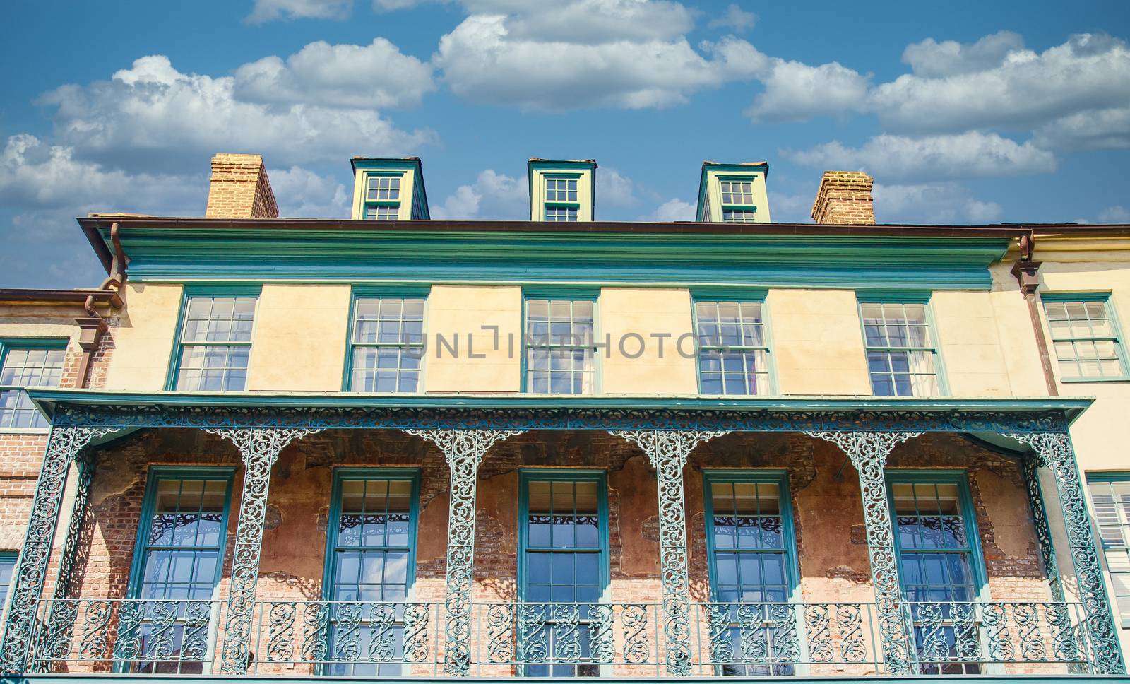 An old yellow and green building with iron balconies