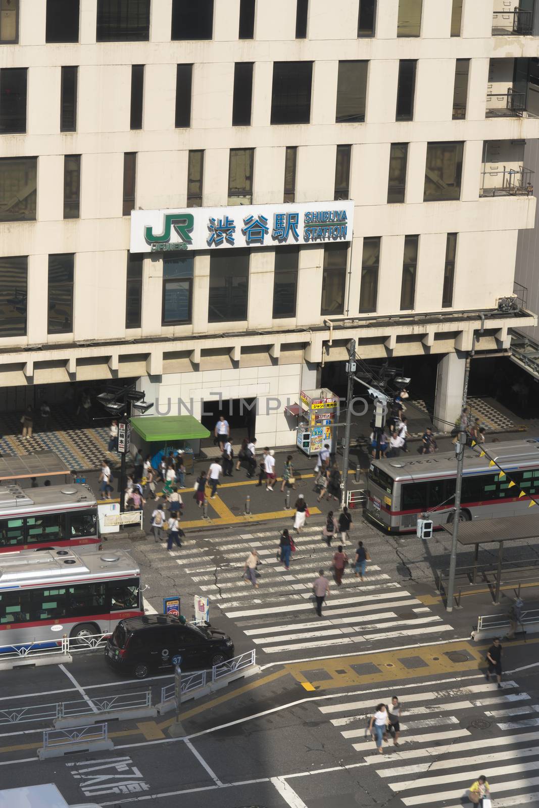 View of the southern exit of Shibuya Station, famous for its moai statue, with buses and taxis stopped at the bus terminal