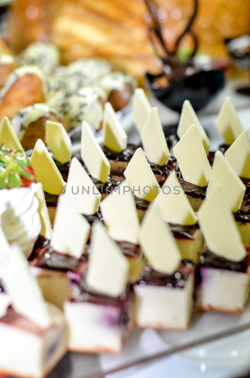 Tray full of cupcakes and slices of cake inside a buffet