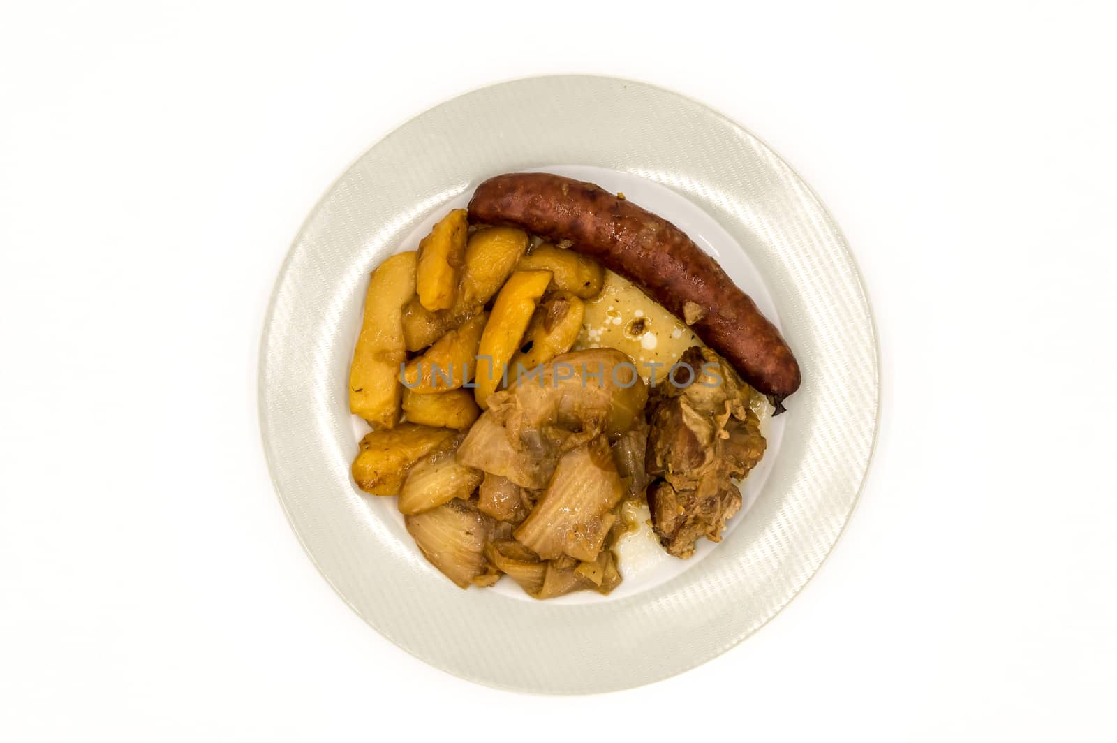 Plate of scorched white cabbage with sausage, potatoes and a piece of lamb viewed from above on a white background