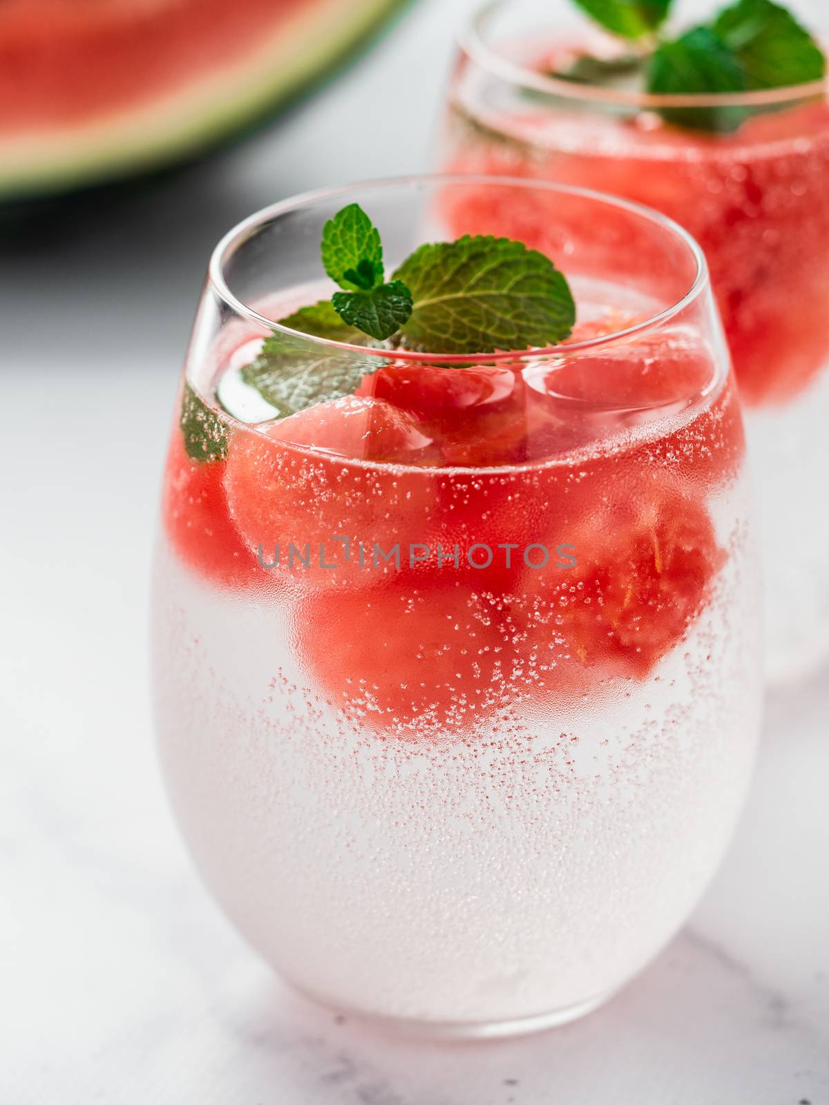 Watermelon ice with sparkling water or soda in glass tumbler. Summer party idea and recipe, add color and flavor for soda or other drink. Vertical