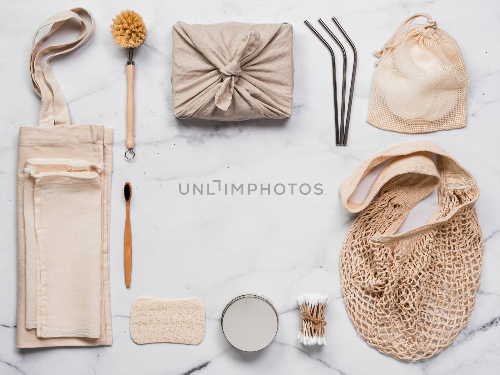 Zero waste concept. Textile wrapping gift, eco bags, metal straws, eco-friendly kitchen tools, bamboo toothbrush and cotton buds, reusable cotton pads on white marble background. Copy space, top view