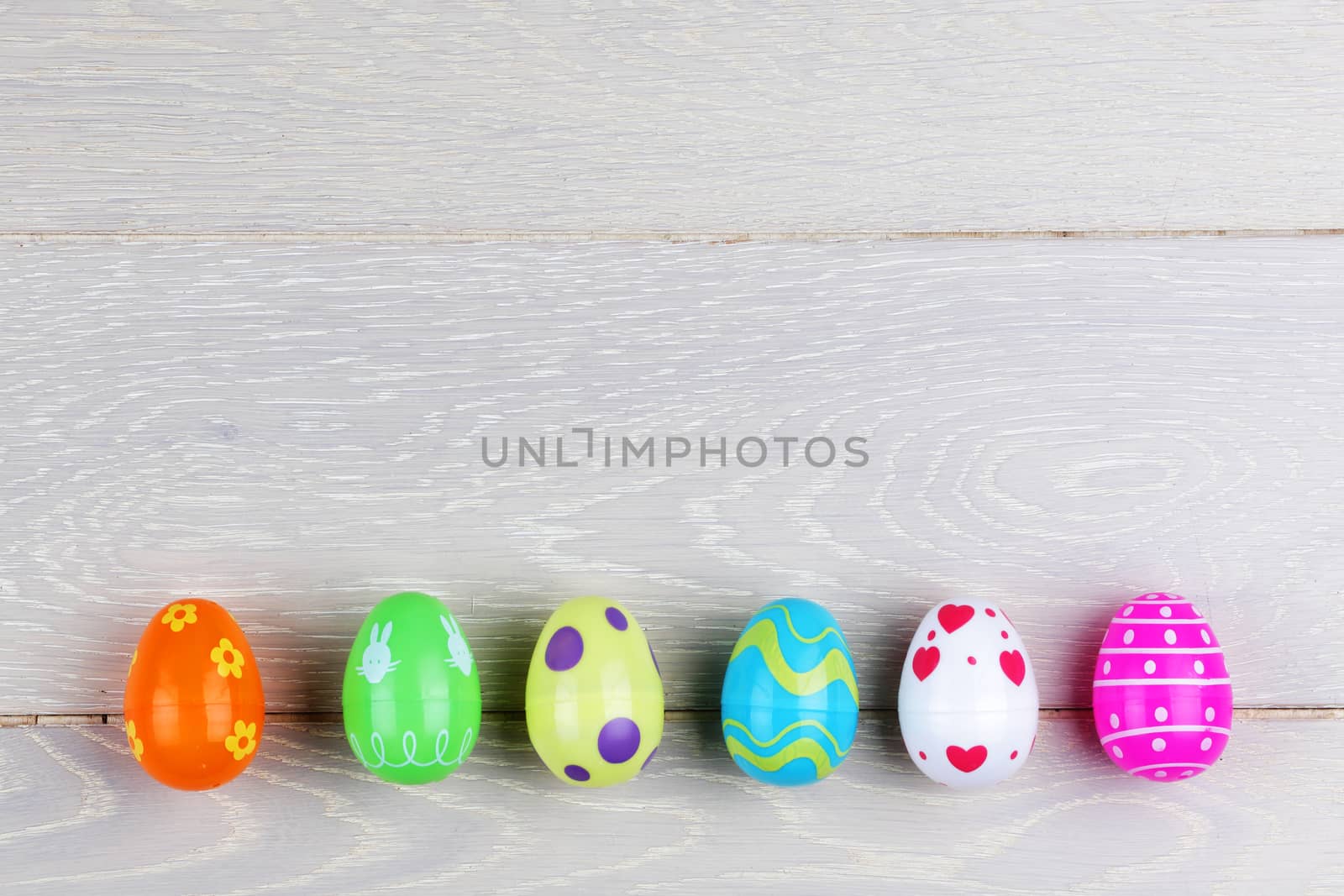 A Light wood surface with plastic easter eggs and copy space